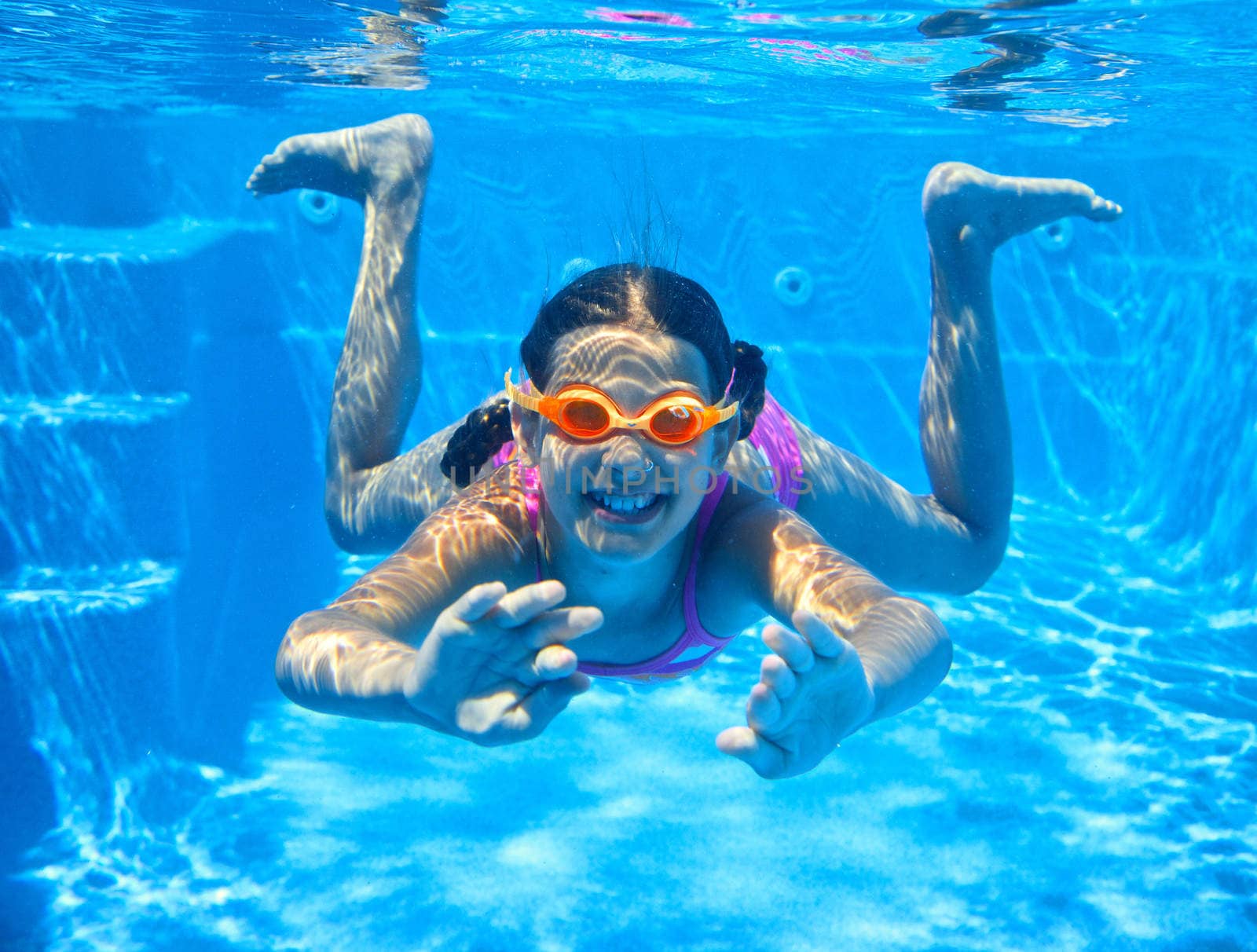 The cute girl swimming underwater and smiling