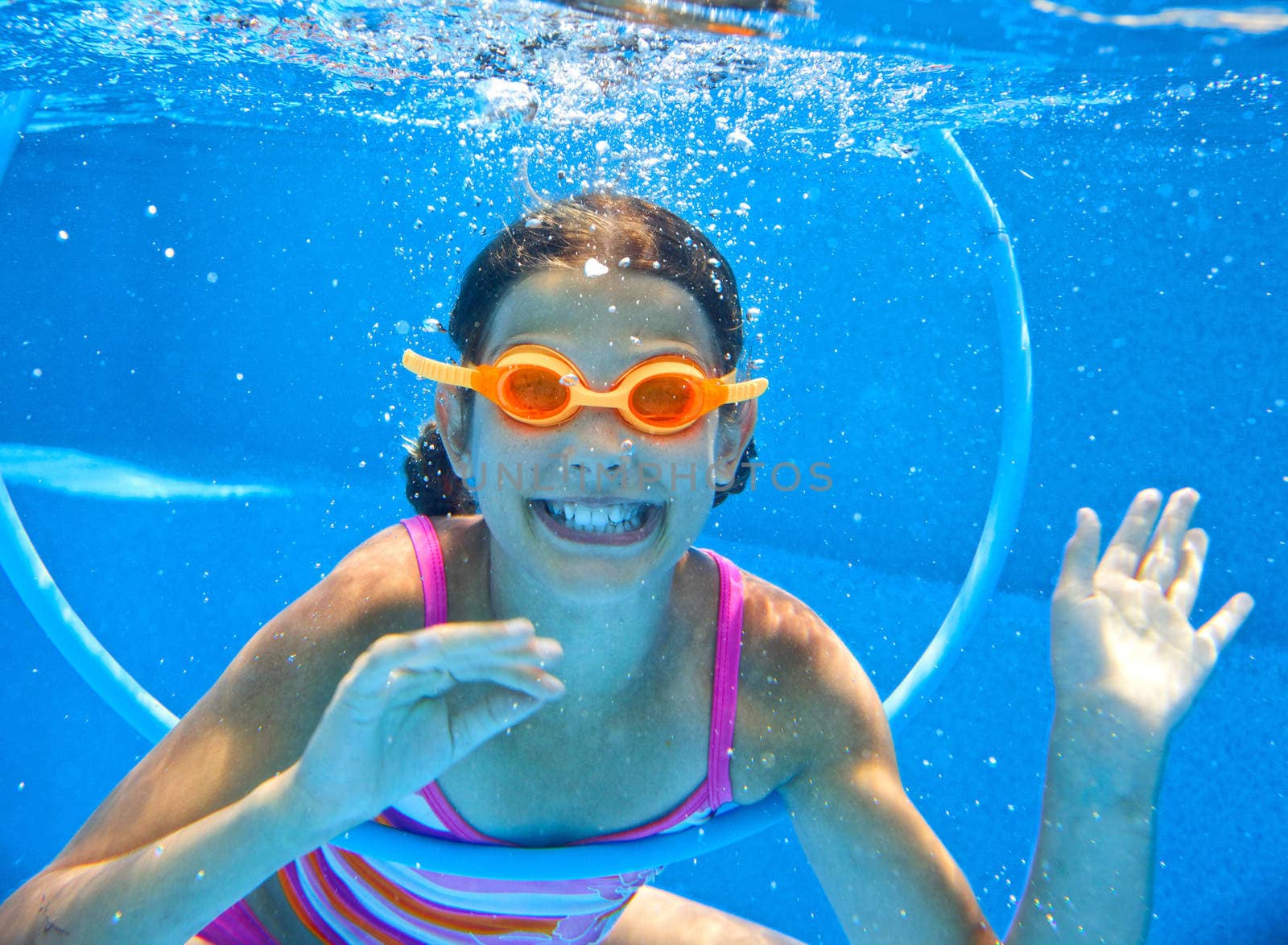 The cute girl swimming underwater and smiling