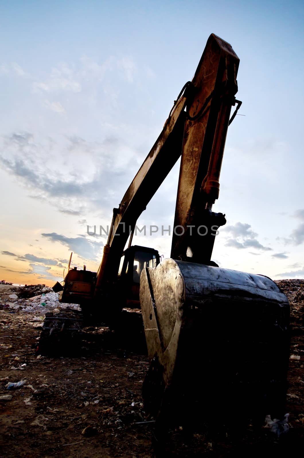 silhouette excavator near garbage heap