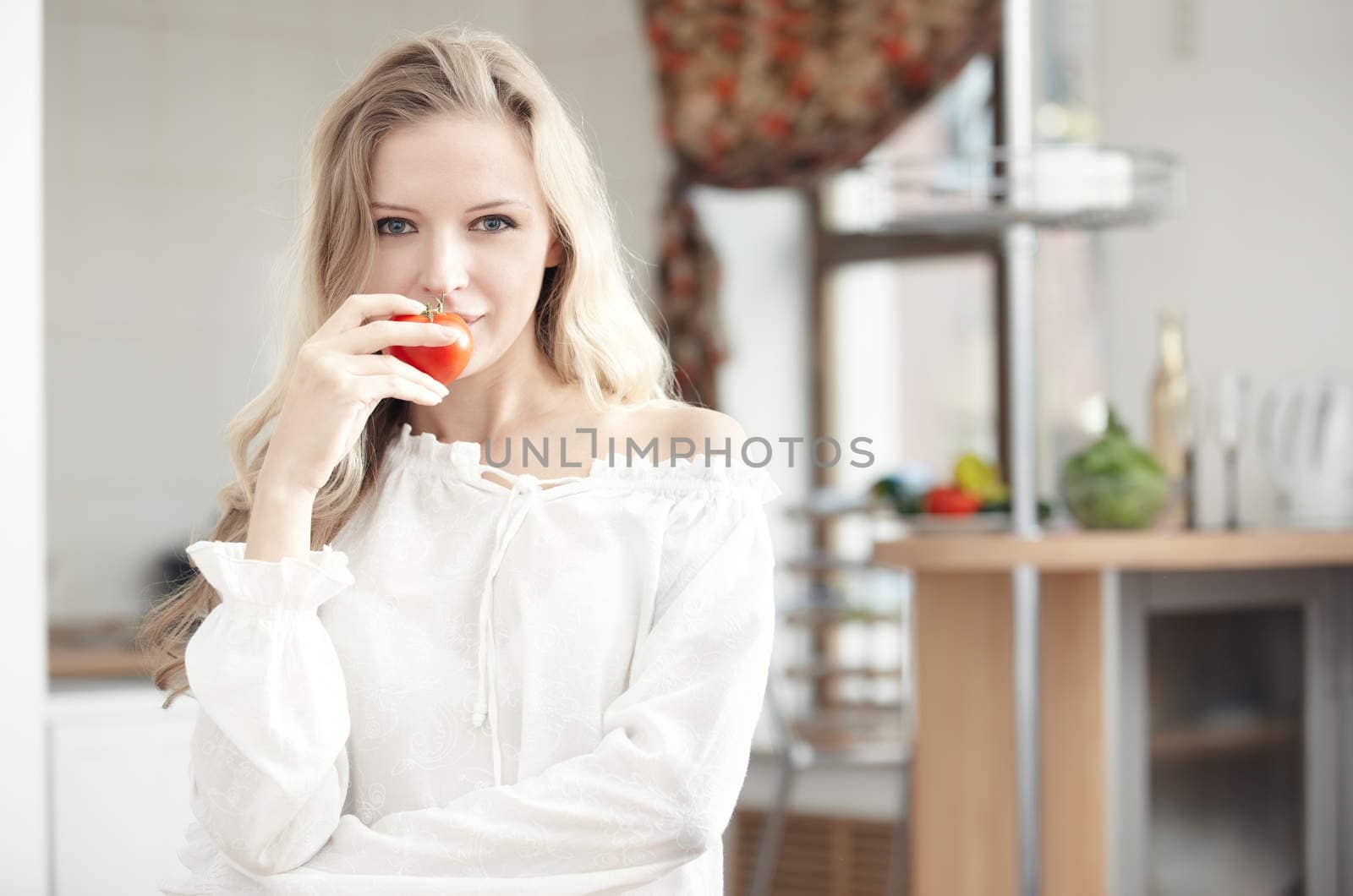 Blond lady with ripe tomato at the kitchen