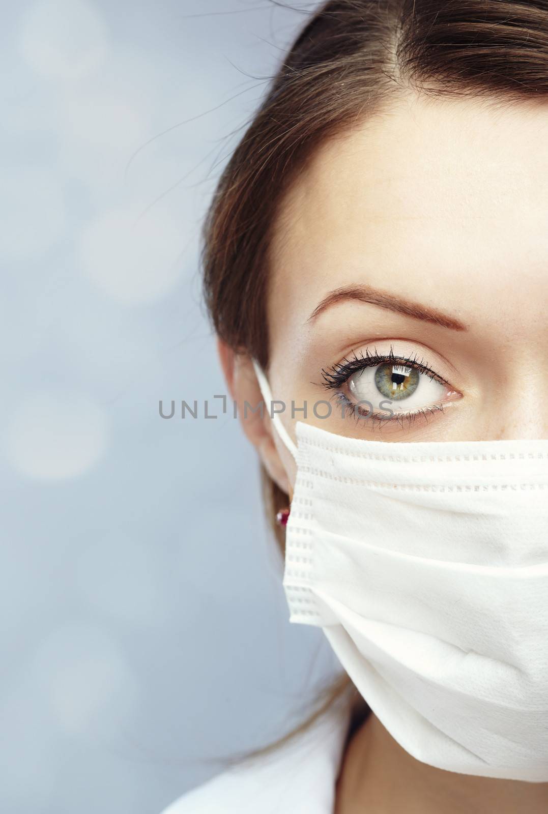 Female doctor on a blue blurred background in the face mask against flue infection