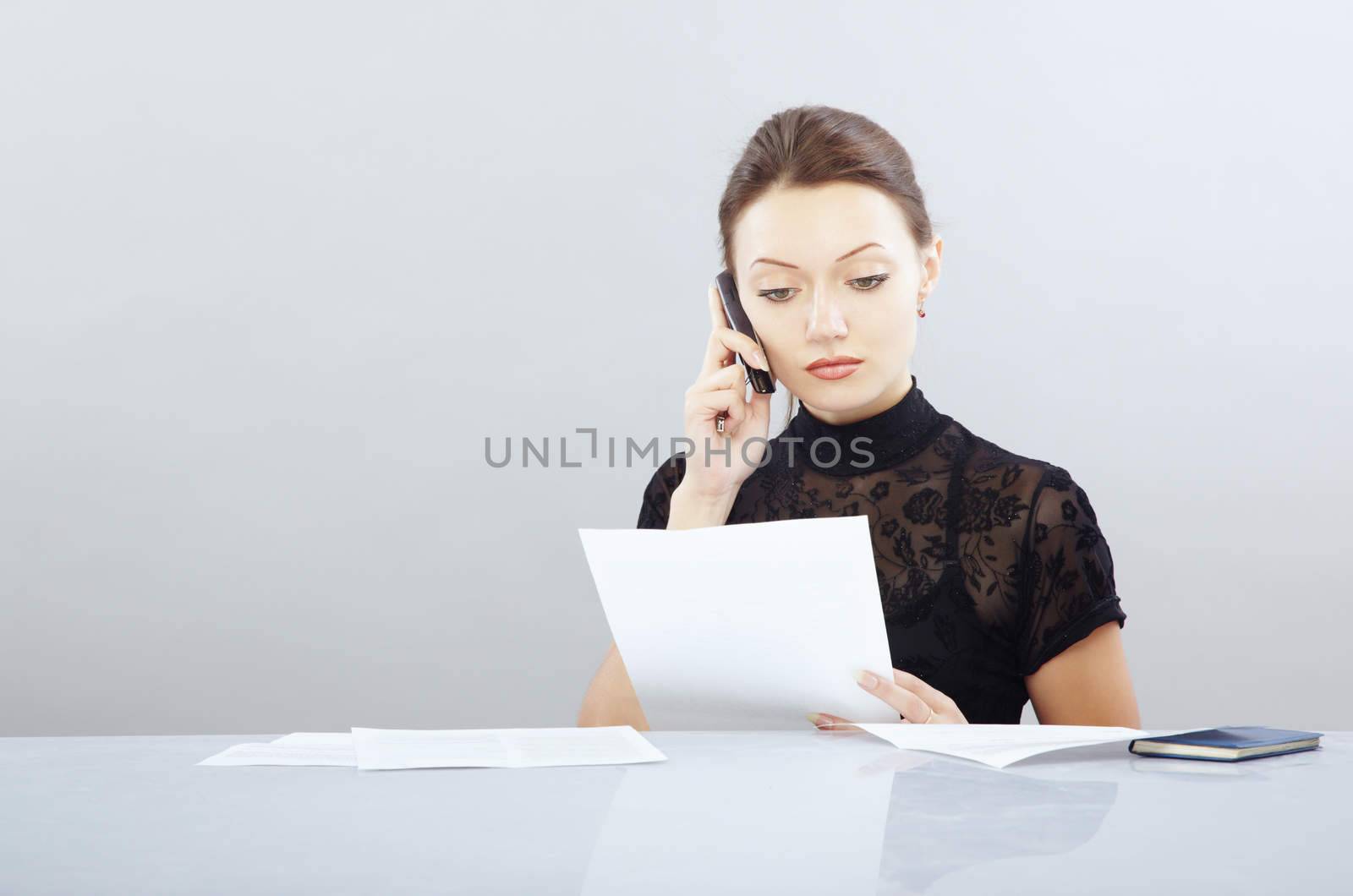 Young businesswoman working with documentation and calling phone