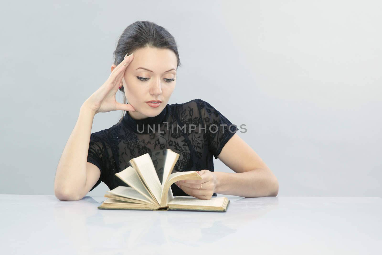 Young female student reads and turns pages of book