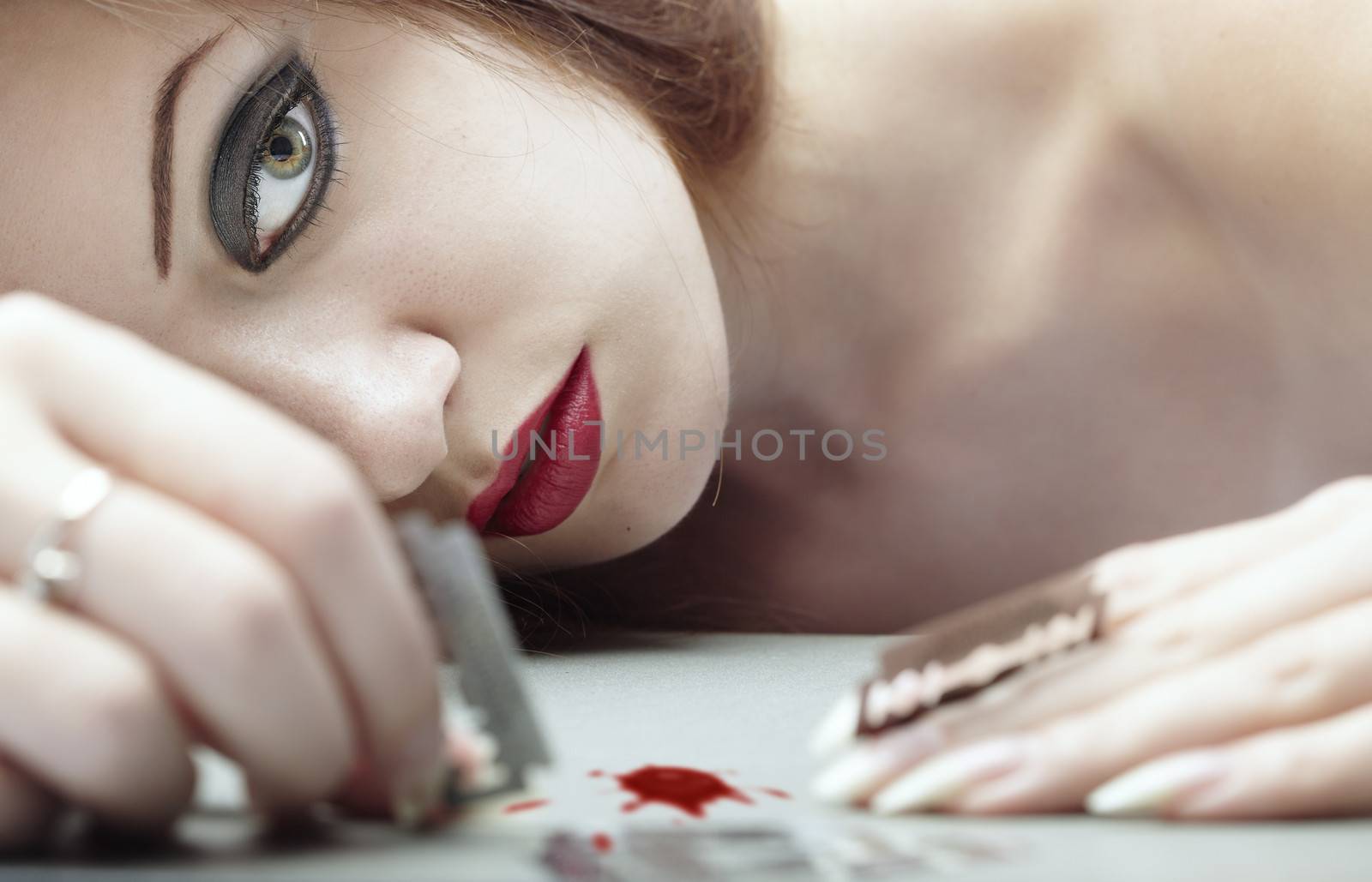 Depressed bleeding lady playing with razors