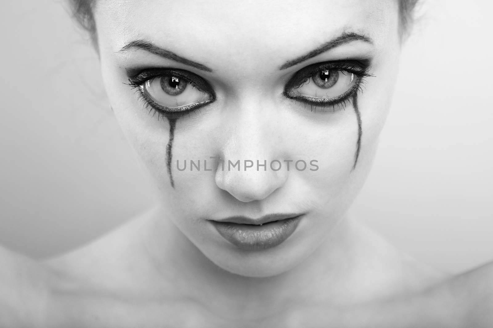 Close-up portrait of the crying woman with washed out mascara. Monochrome photo