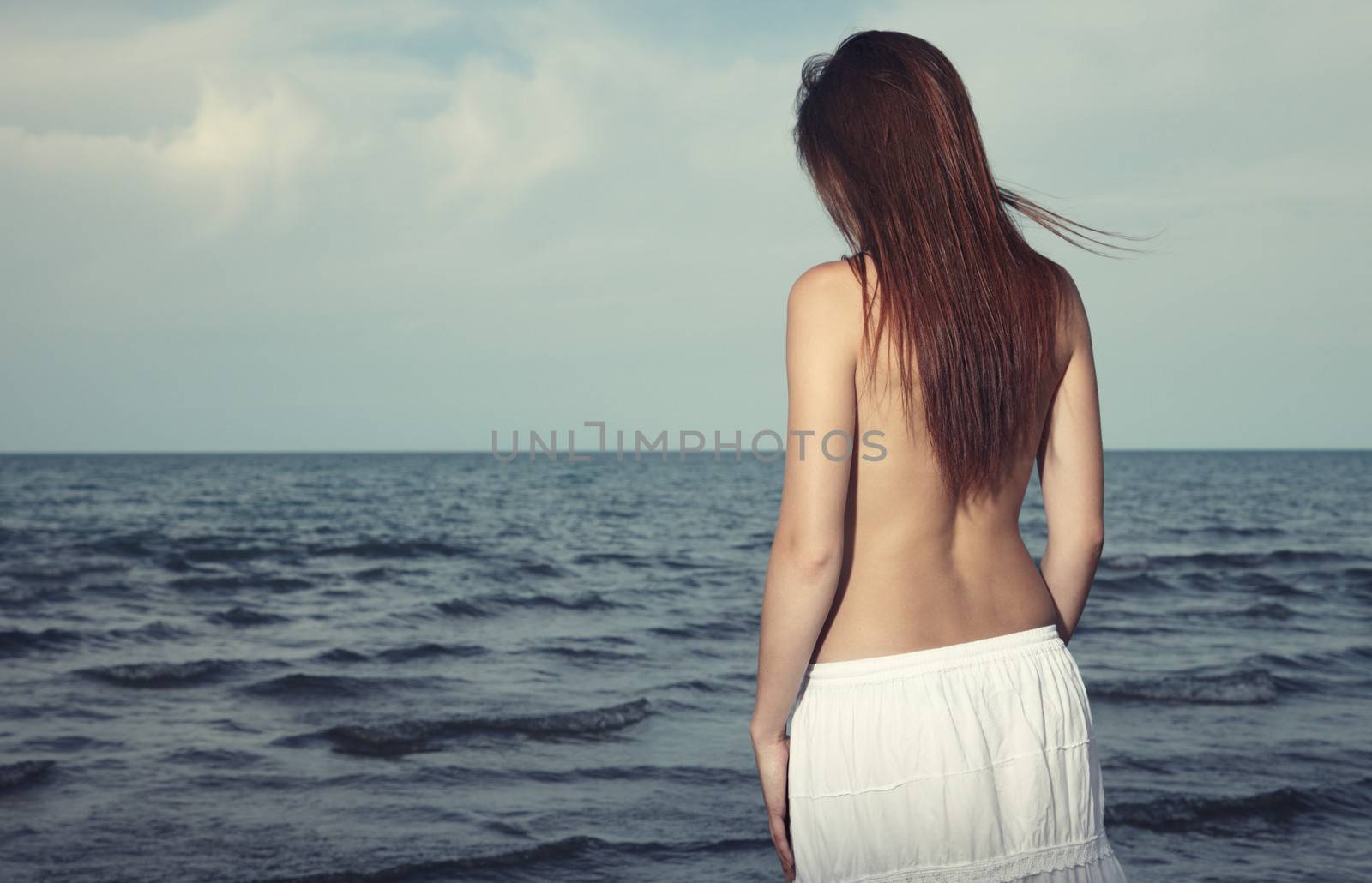 Rear view on the lonely woman sadding at the sea