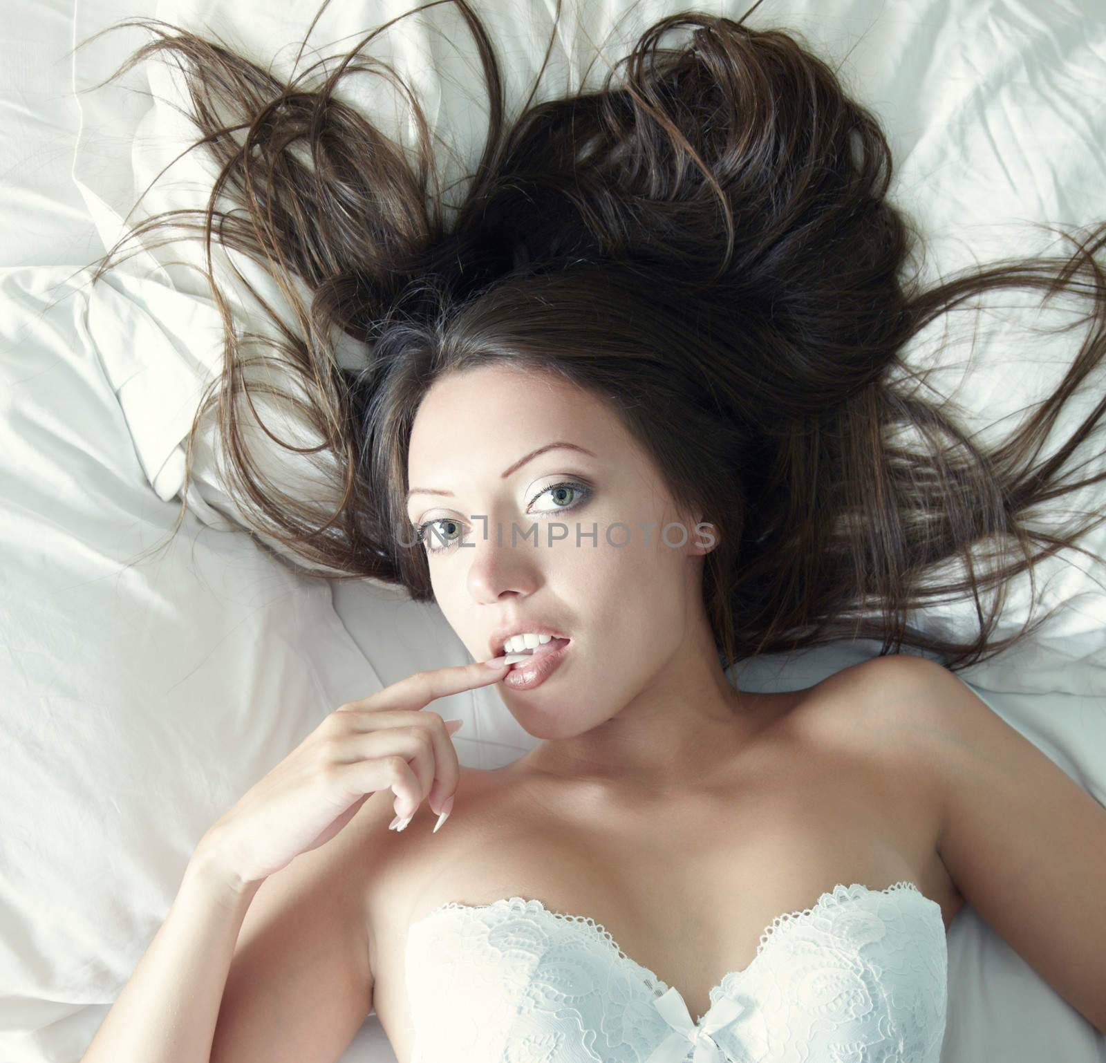 Pretty lady in camisole lays on the bed. Natural light and colors