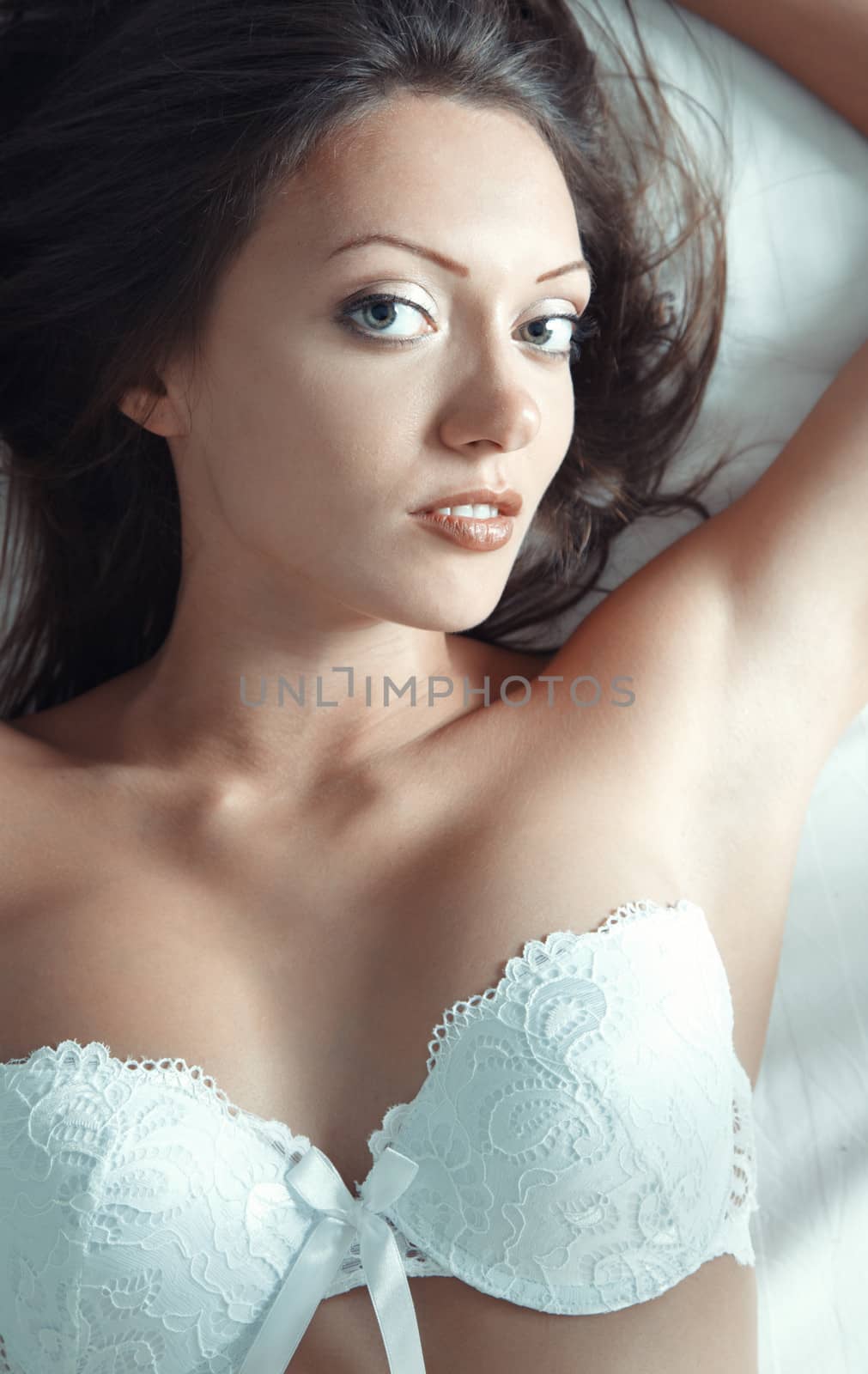 Sexy lady with white camisole laying and pampering on the bed. Natural light and colors