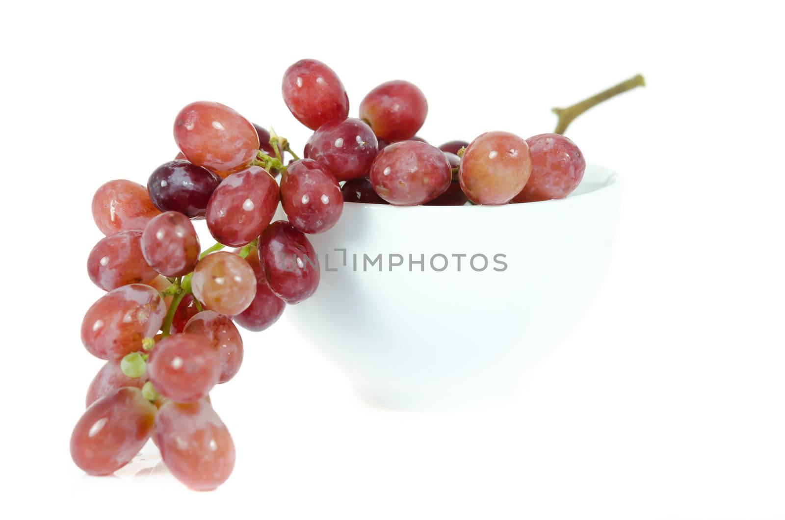 close up  of red grapes in bowl  on white