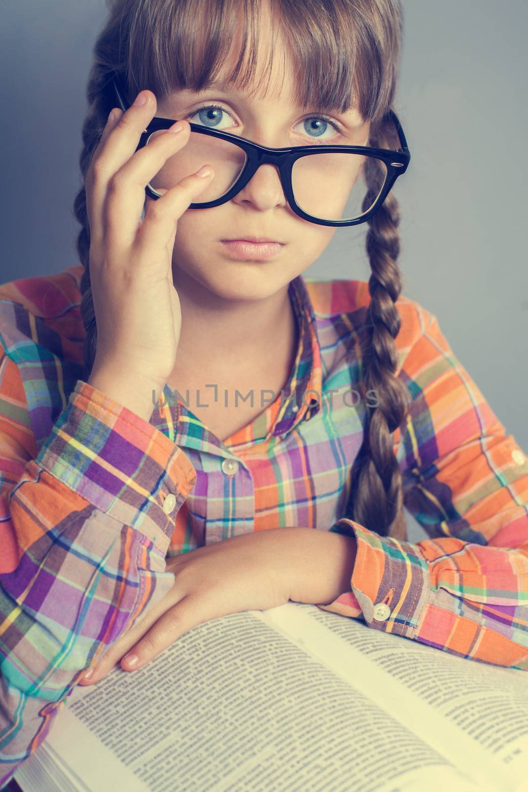 Cute little girl with books while wearing glasses