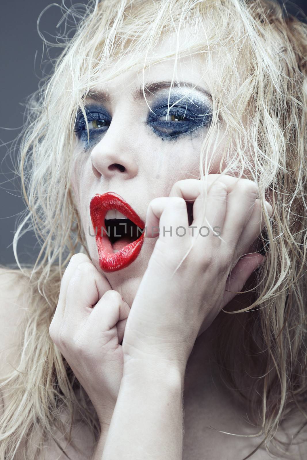 Crazy blond lady with bizarre makeup. Vertical portrait. Artistic colors added