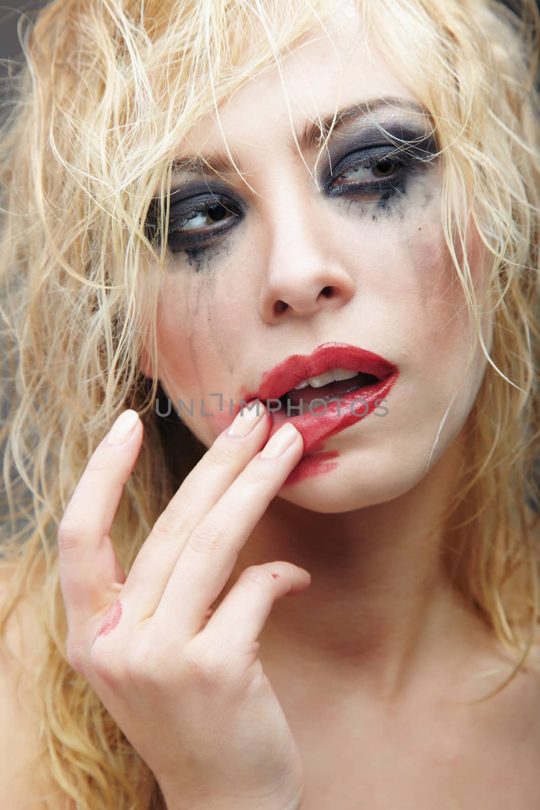 Beautiful blond lady with strange makeup smearing lipstick. Artistic colors added