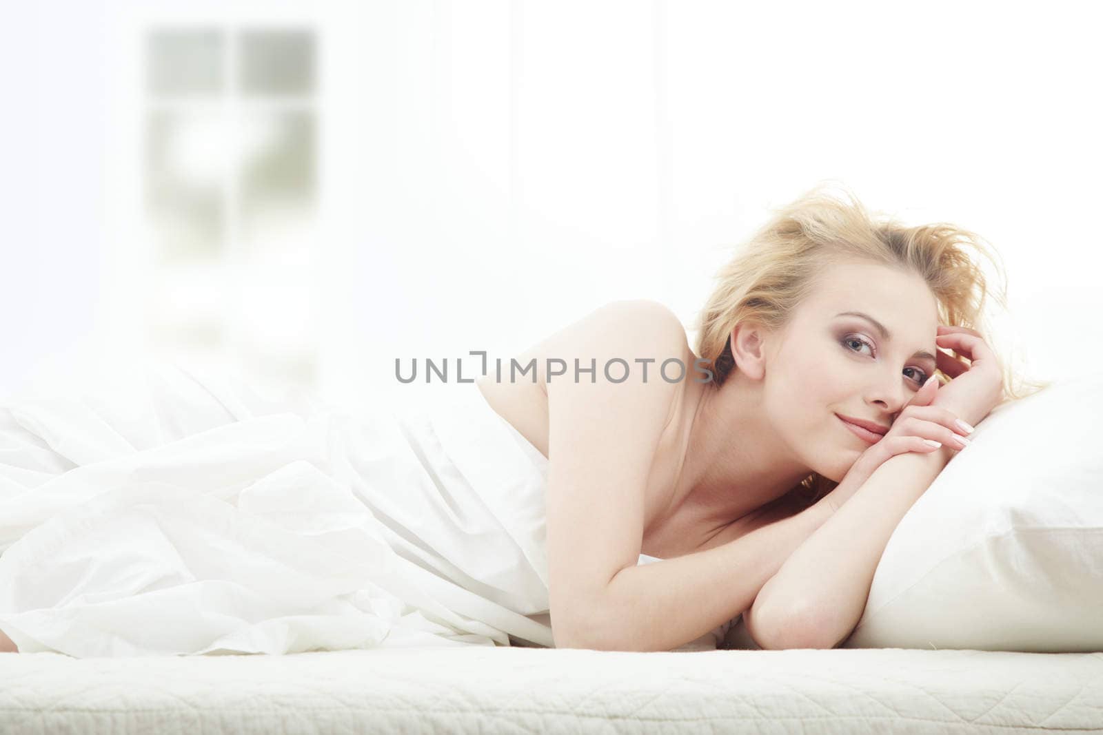 Blond lady laying in bedroom at early morning