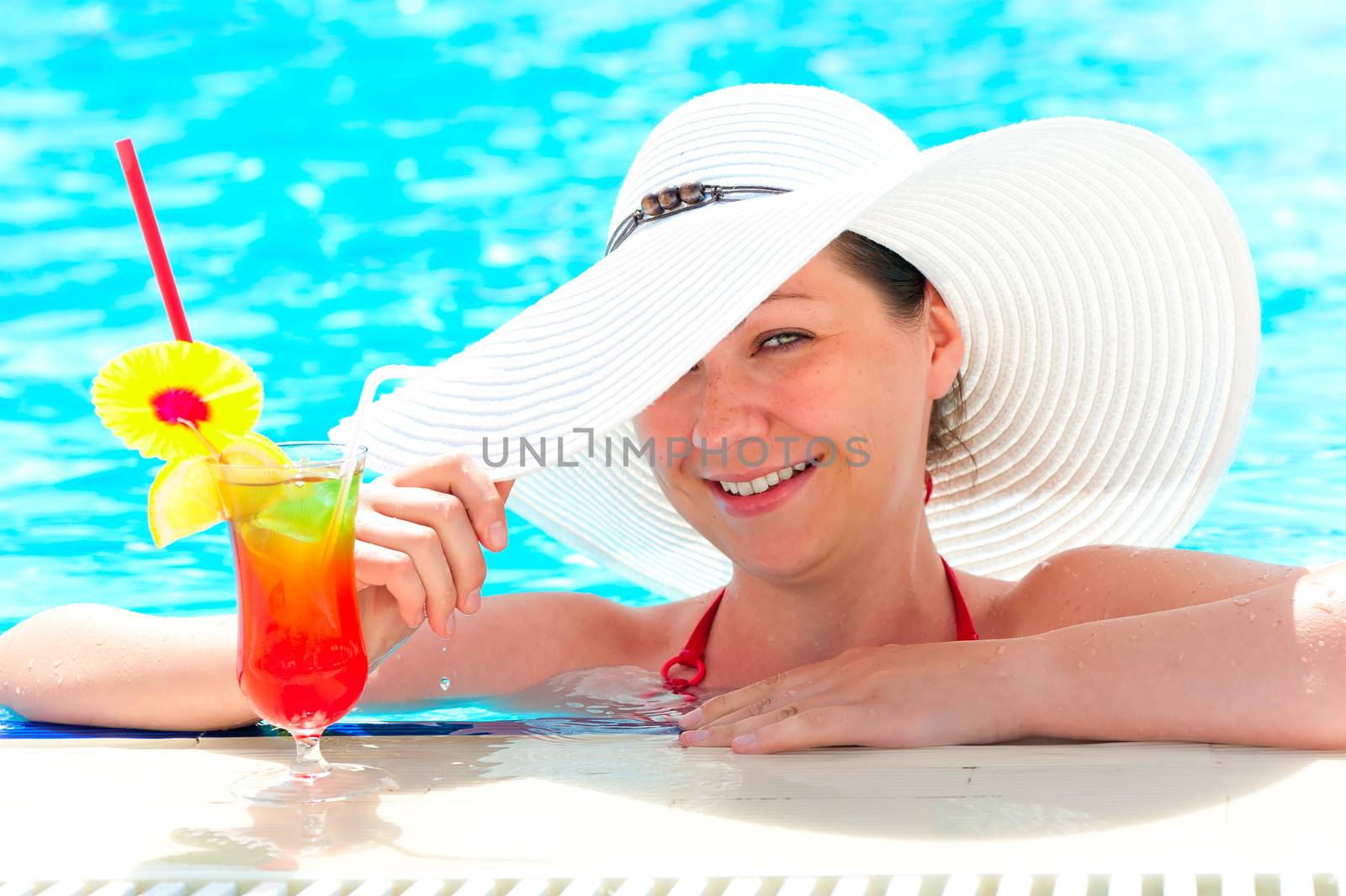 happy girl with a cocktail at the pool holding a hat hand by kosmsos111