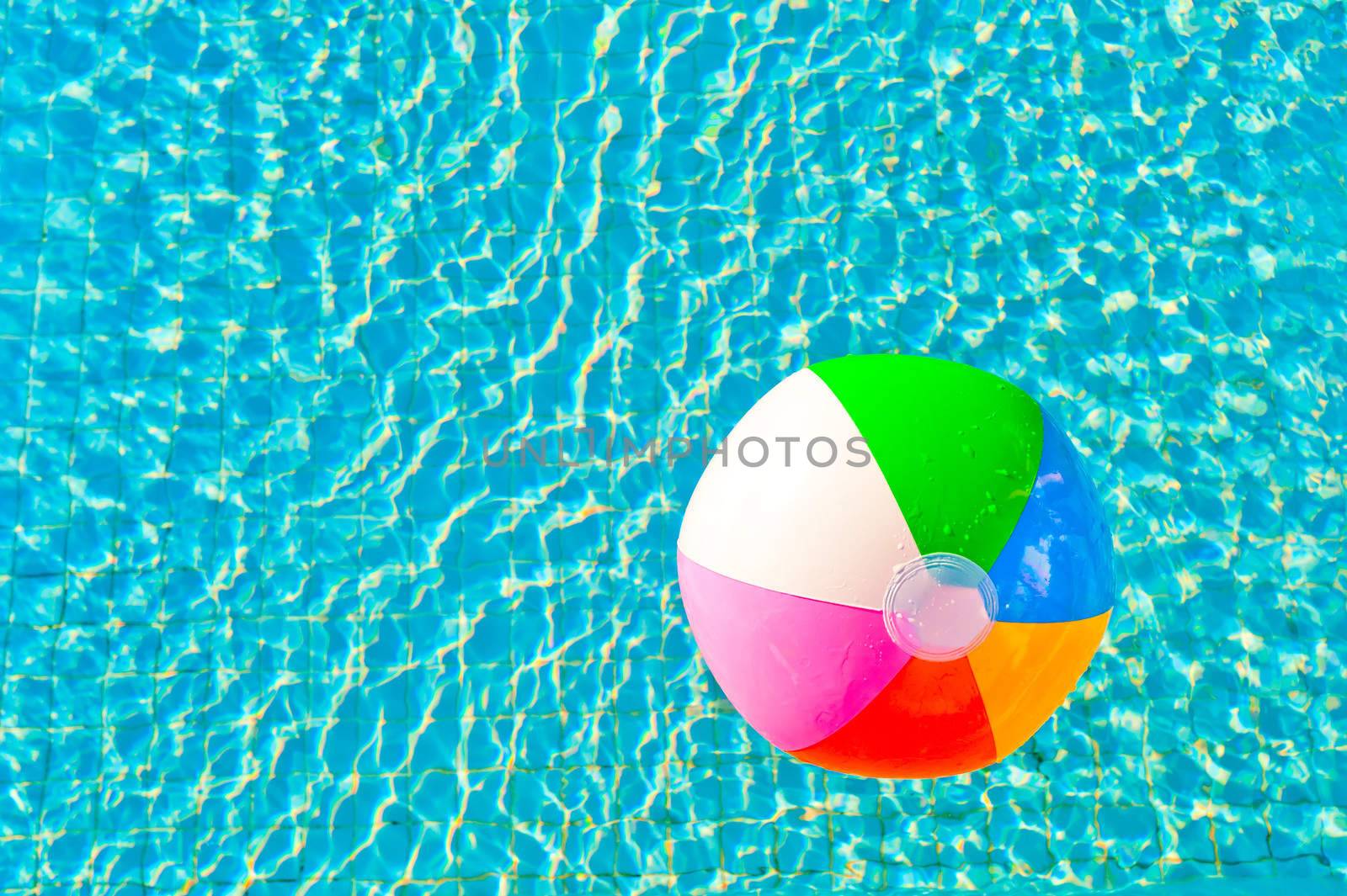 colorful beach ball floating in a pool by kosmsos111
