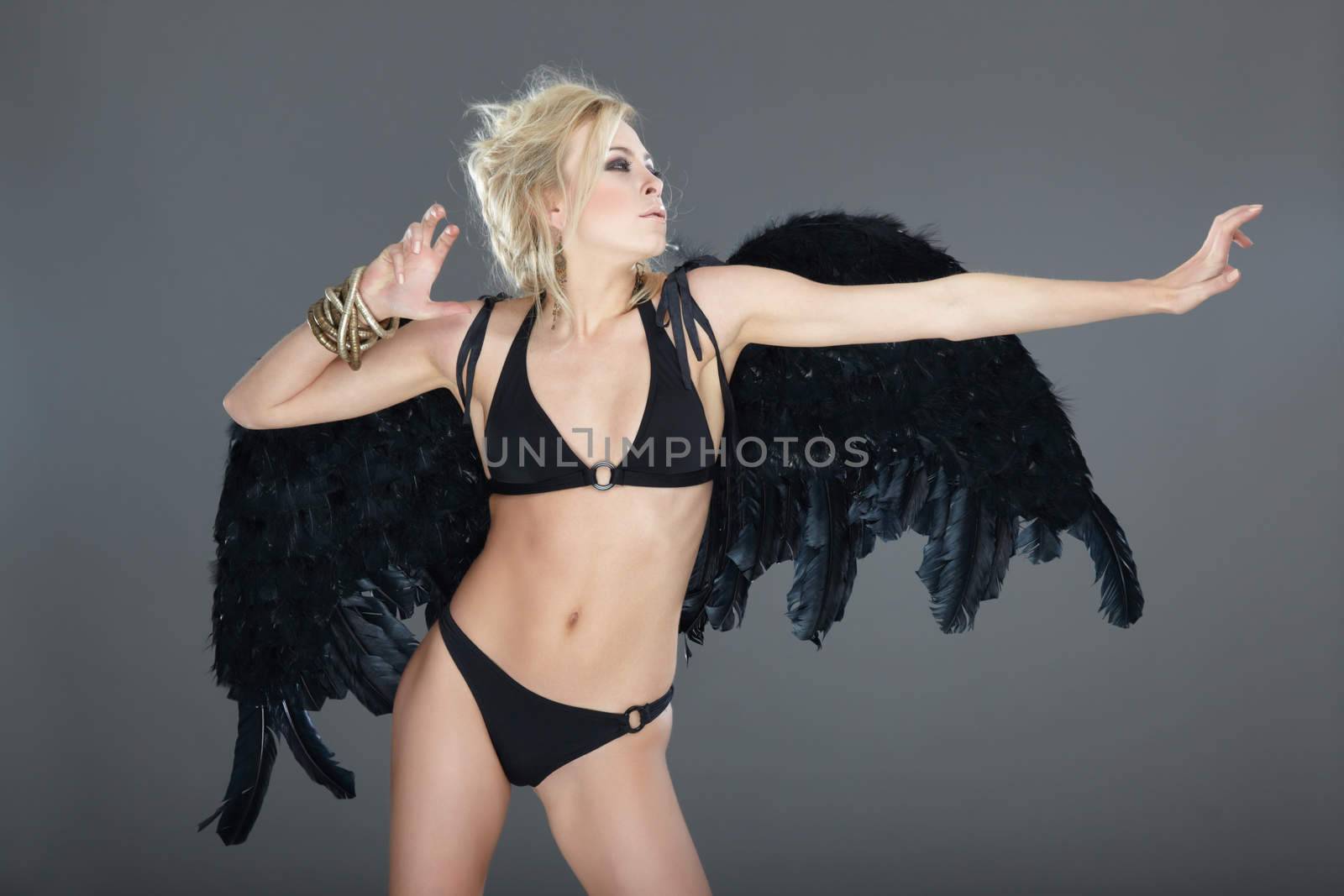 Blond female angel with black angel wings on a gray background