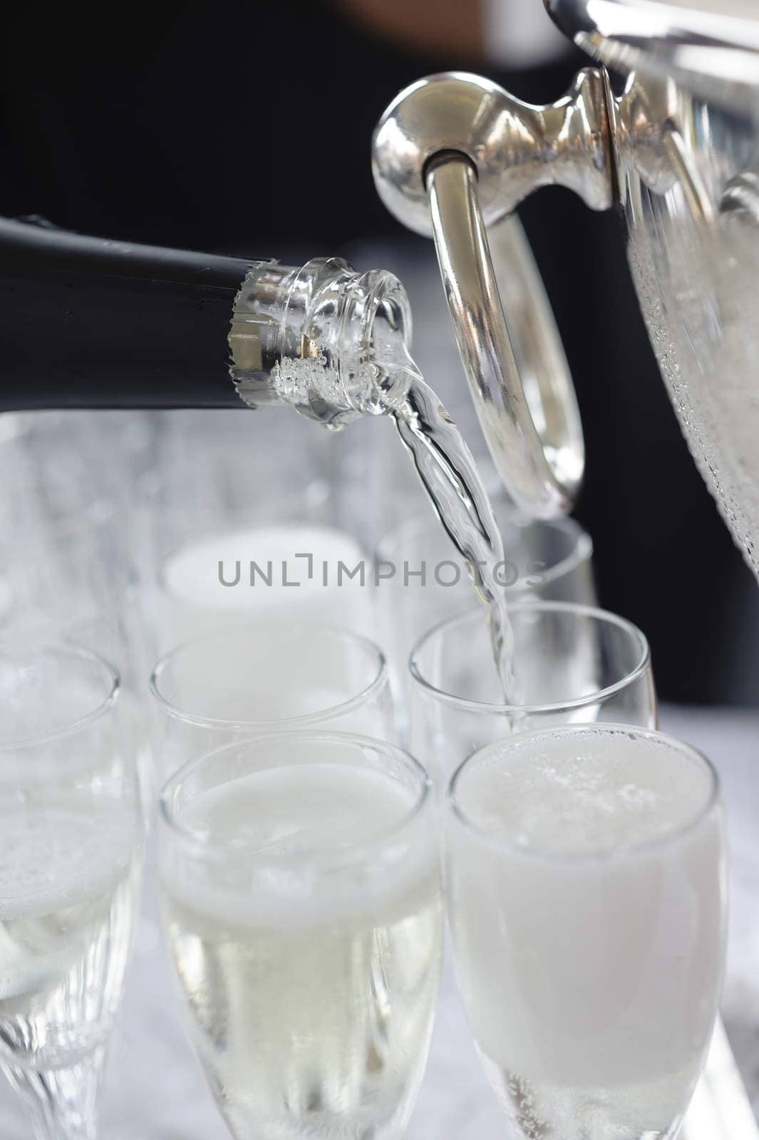 Pouring sparkling beverage on flute glasses