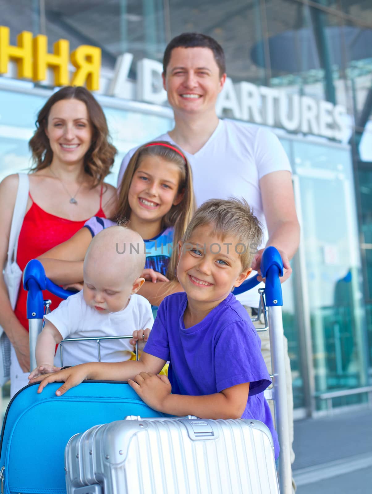 Portrait of traveling family of five with suitcases in airport