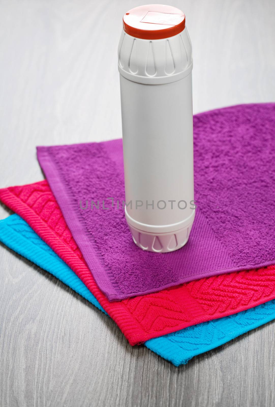 three towels with bottle on wooden background