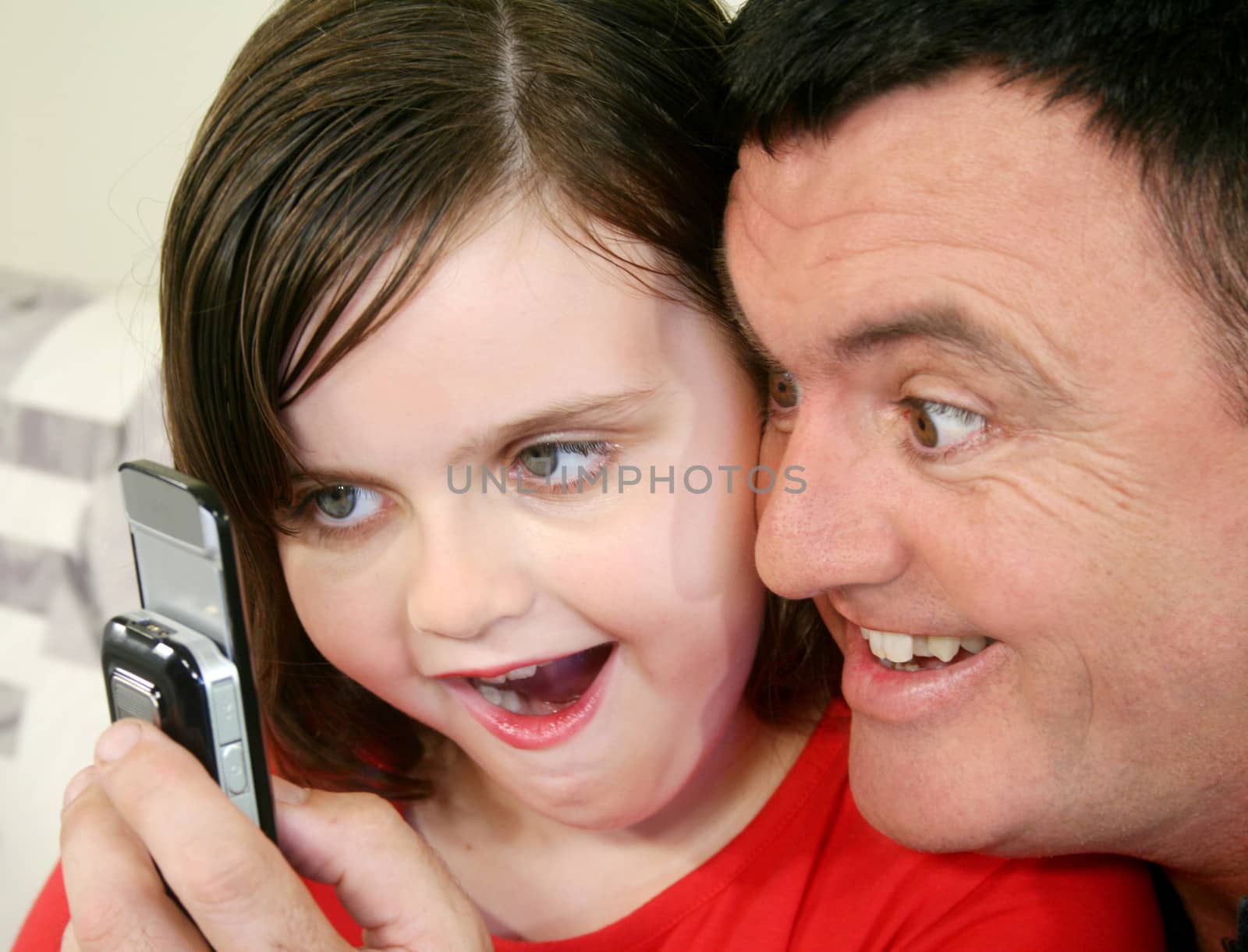 Father and young daughter play a game on her cell phone.