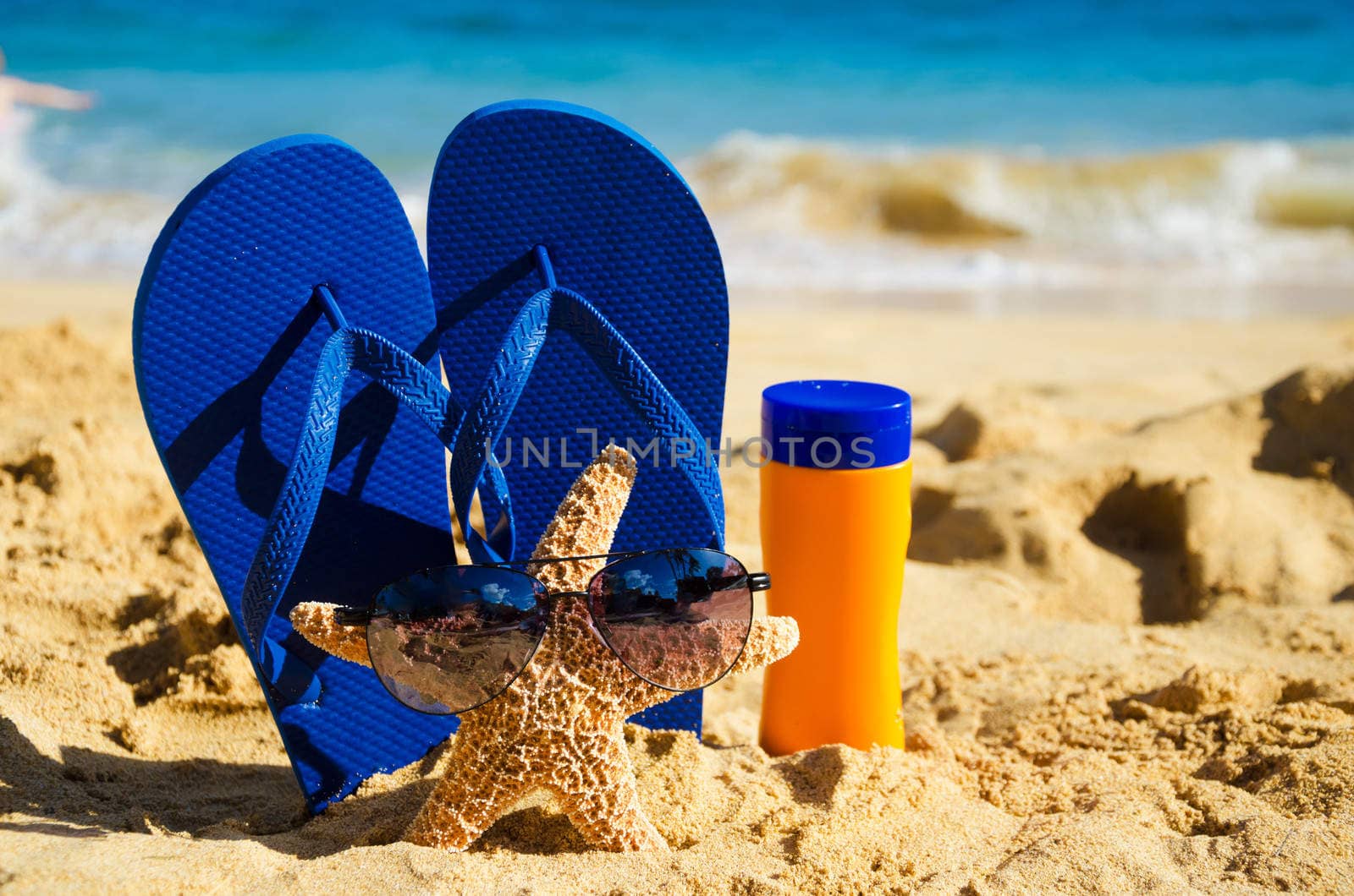 Blue Flip flops, sunscreen and starfish with sunglasses on sandy beach in Hawaii, Kauai