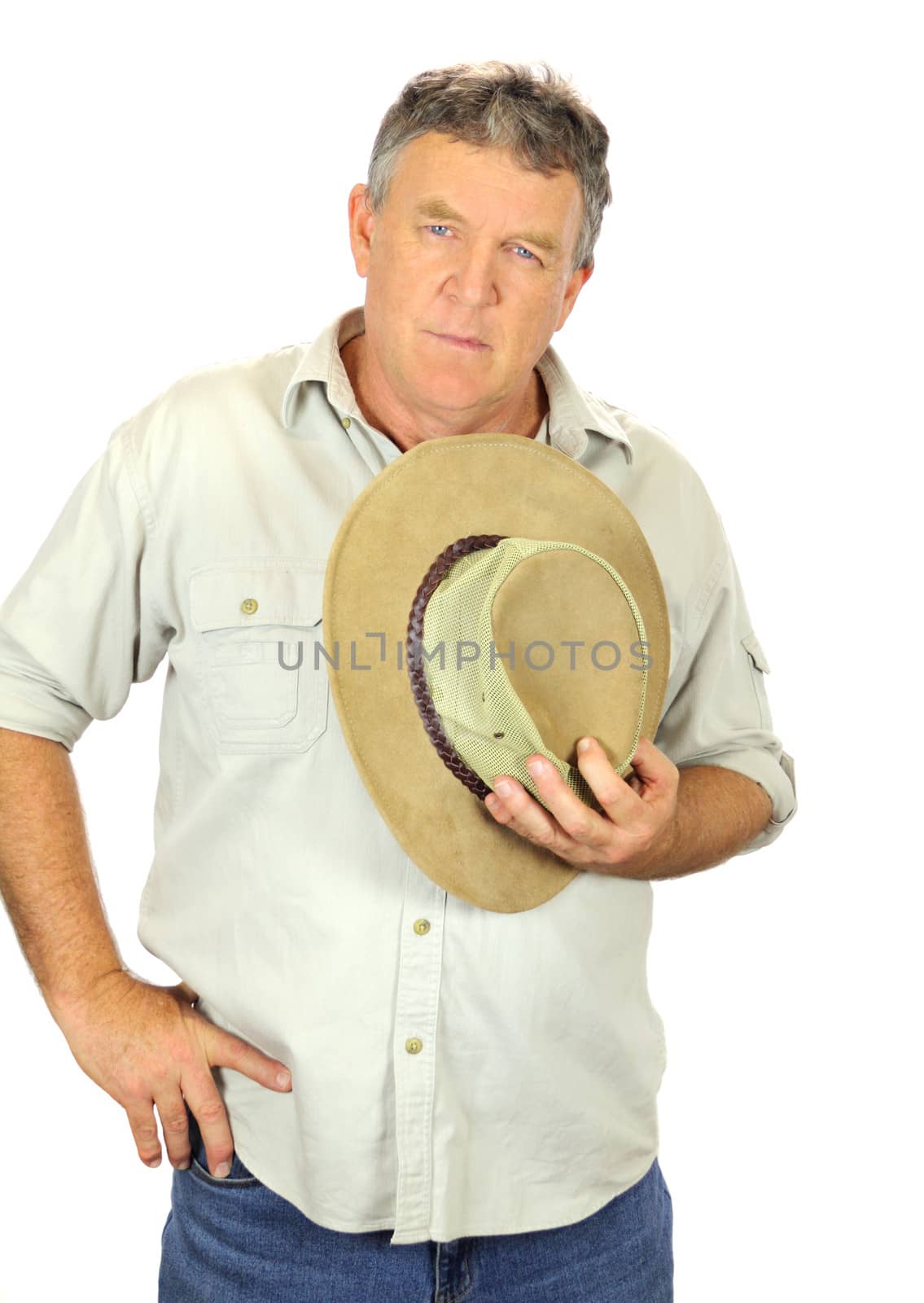 Middle aged man in casual clothes holding a hat to his chest.