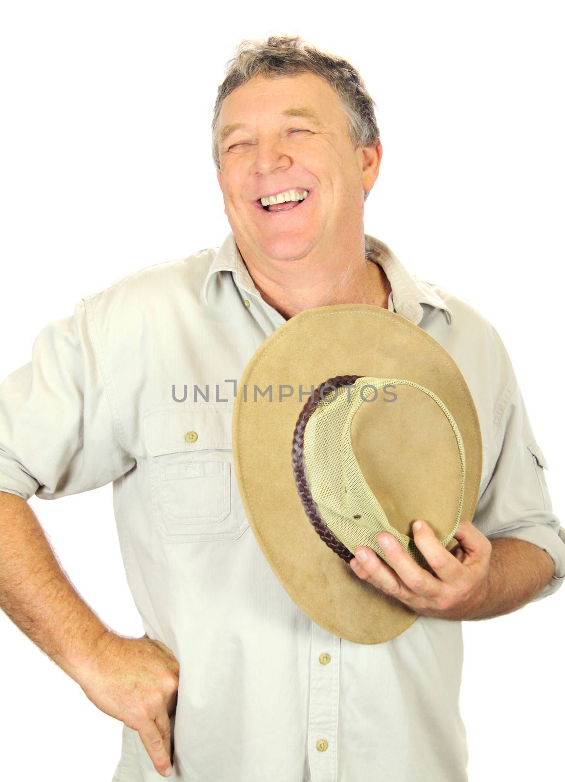 Middle aged laughing man standing and holding hat.
