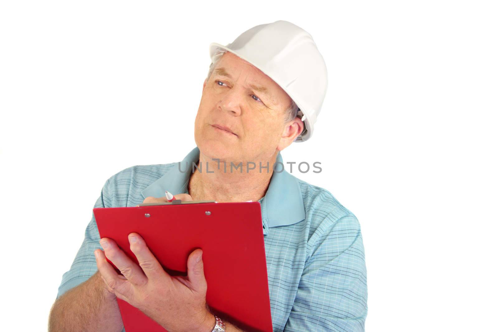Serious middle aged construction foreman with hard hat writing on clipboard.