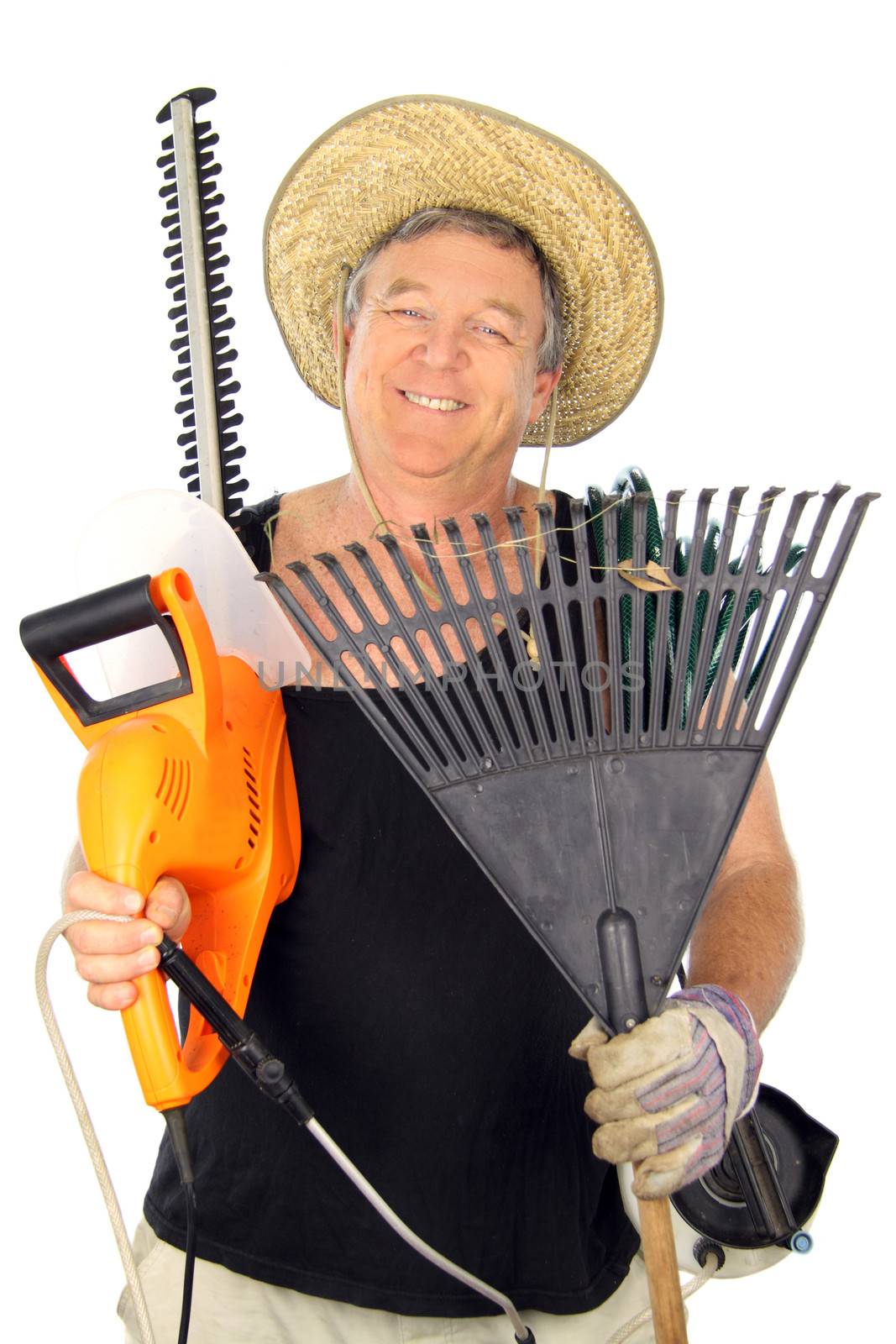 Happy middle aged gardener carrying an array of gardening tools.