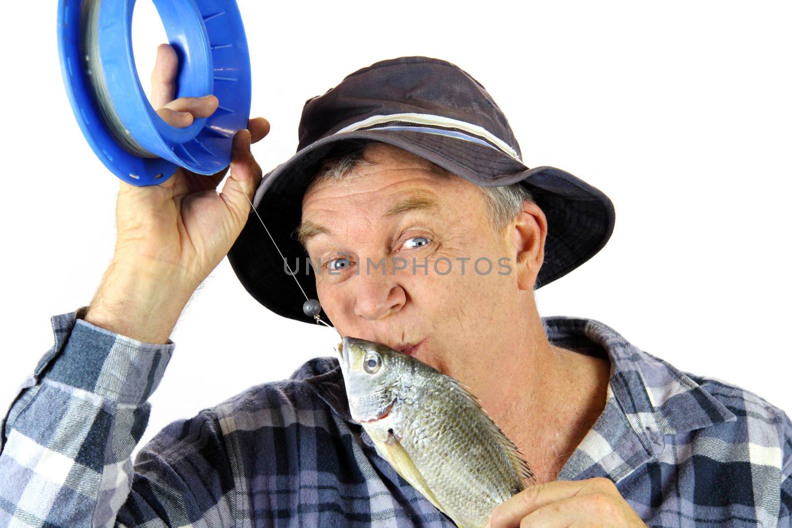 Middle aged fisherman kisses the fish he has just caught.