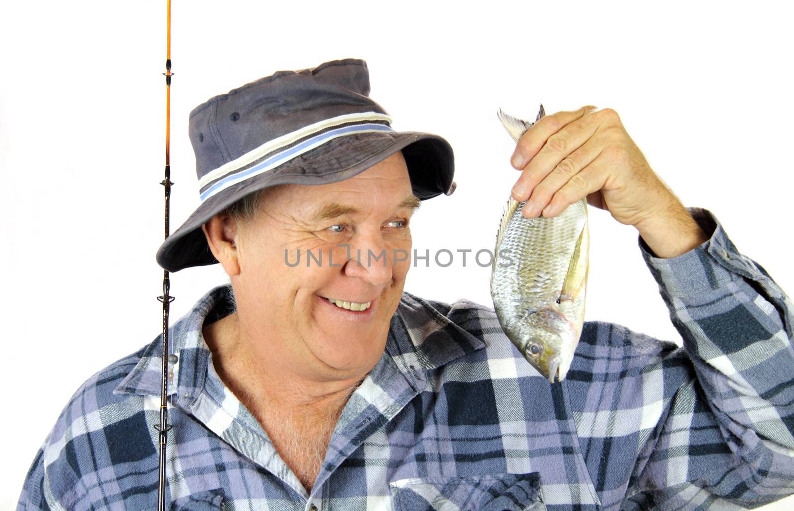 Proud middle aged fisherman holds up the fish he has just caught.