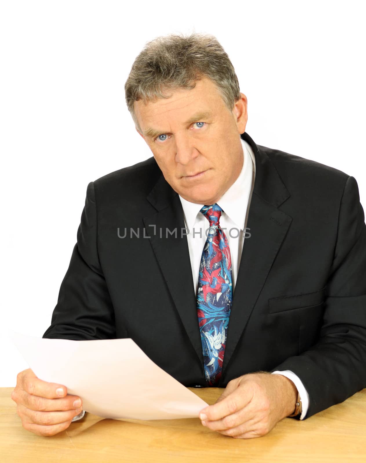 Resolute middle aged businessman with a steely glare sitting at desk.