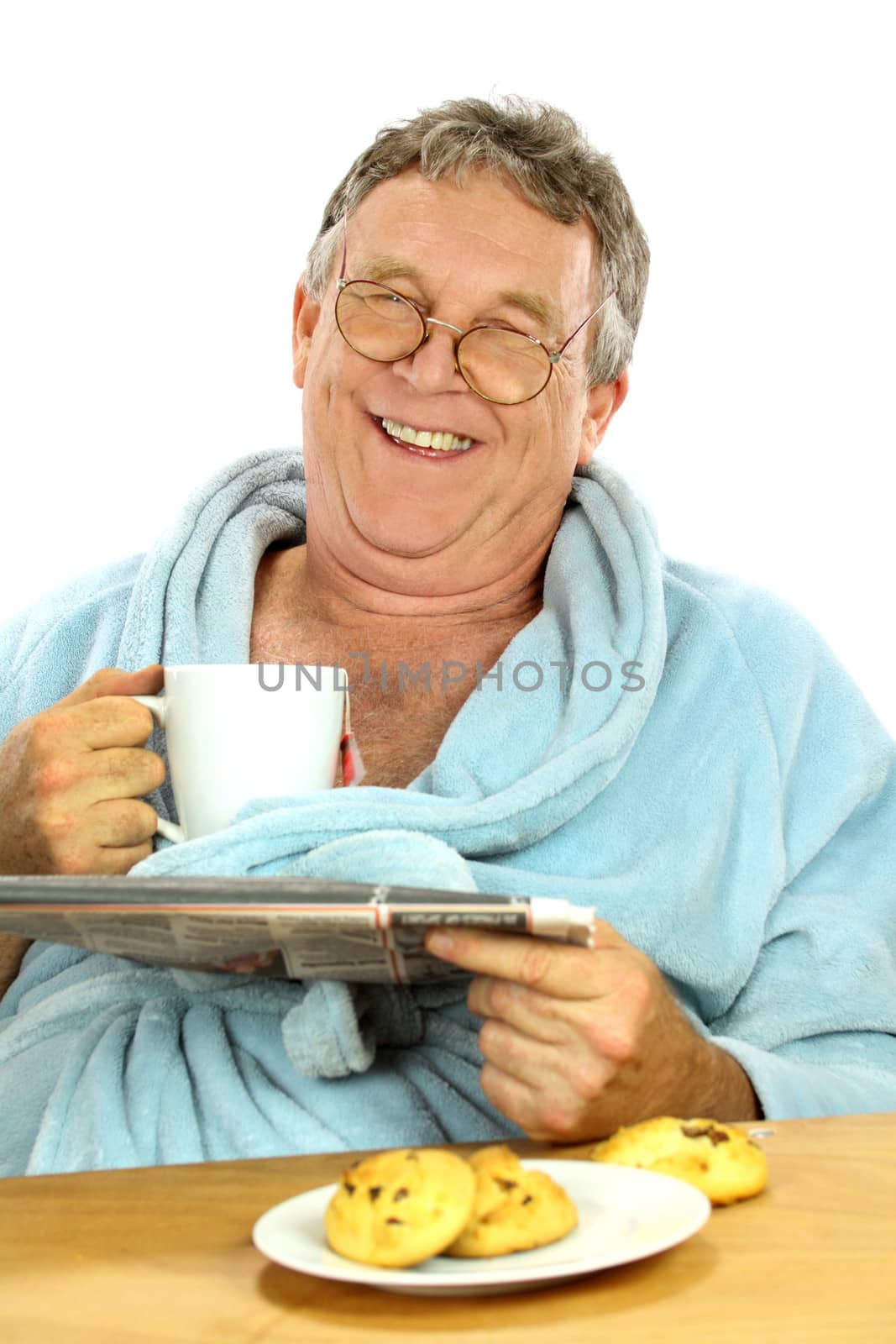 Nerdy middle aged man smiling while having breakfast and reading the paper.