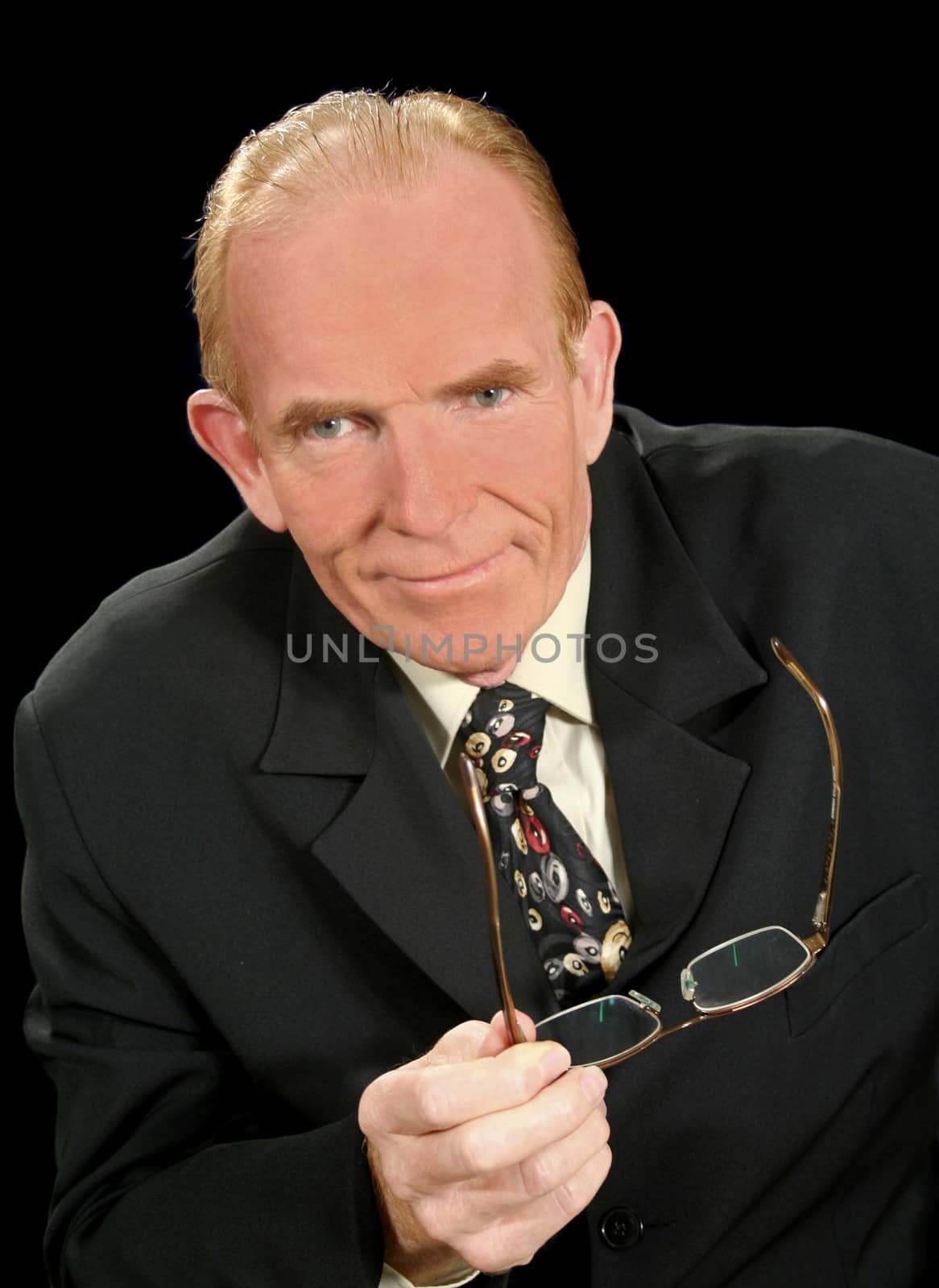 Middle aged businessman looking smug and holding glasses.