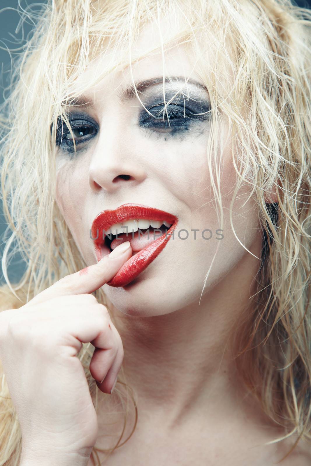 Young blond lady with bizarre makeup. Vertical studio photo. Artistic colors added