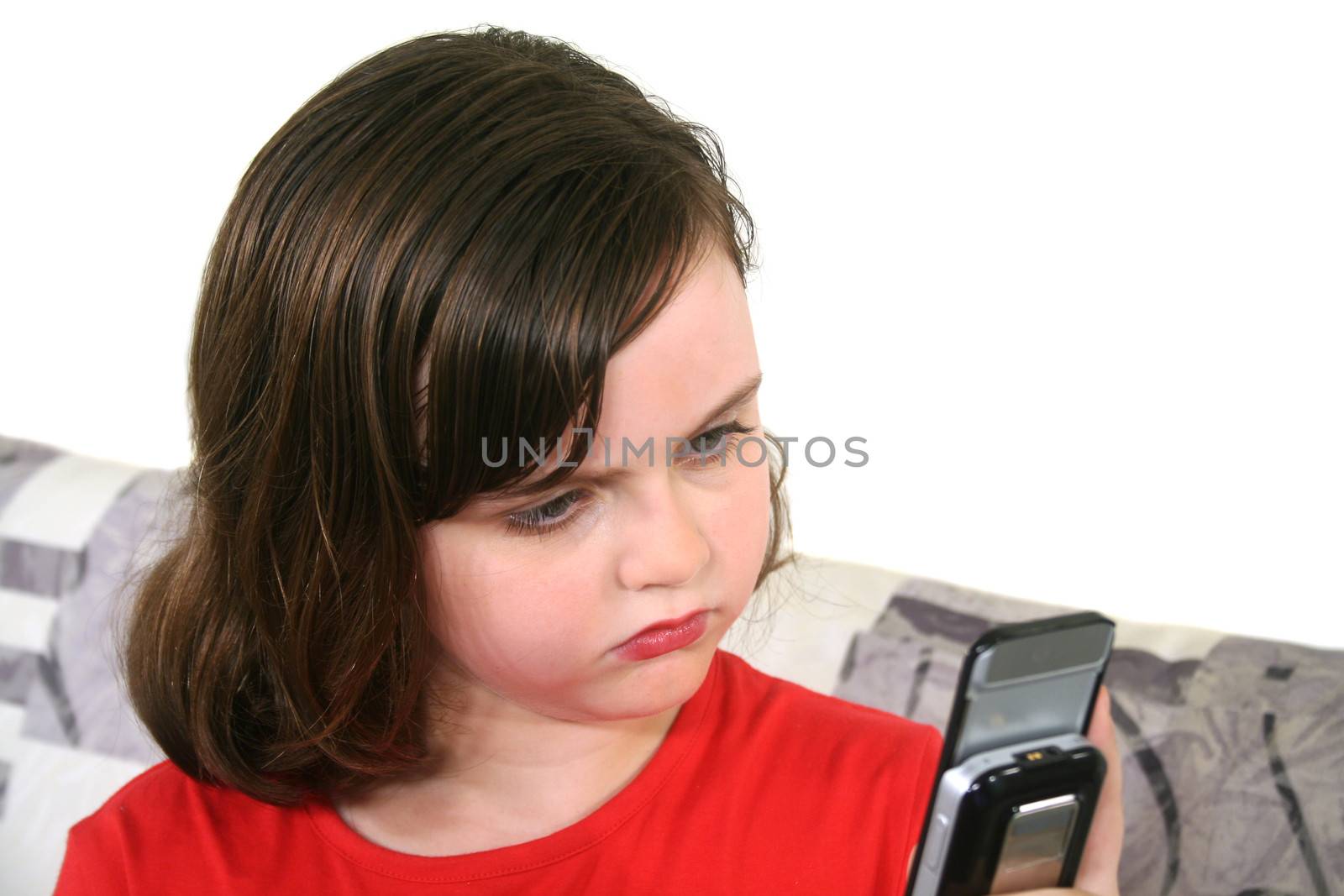 Cute little girl sending a text message on her cell phone.