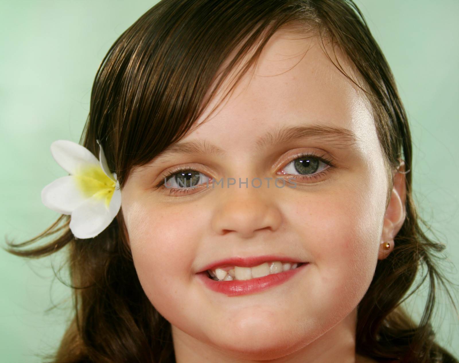 Happy and contented little girl with a frangipani in her hair.