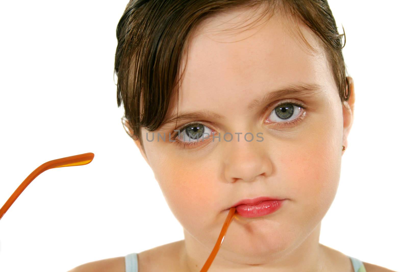 Little girl with a serious look with glasses to her mouth.