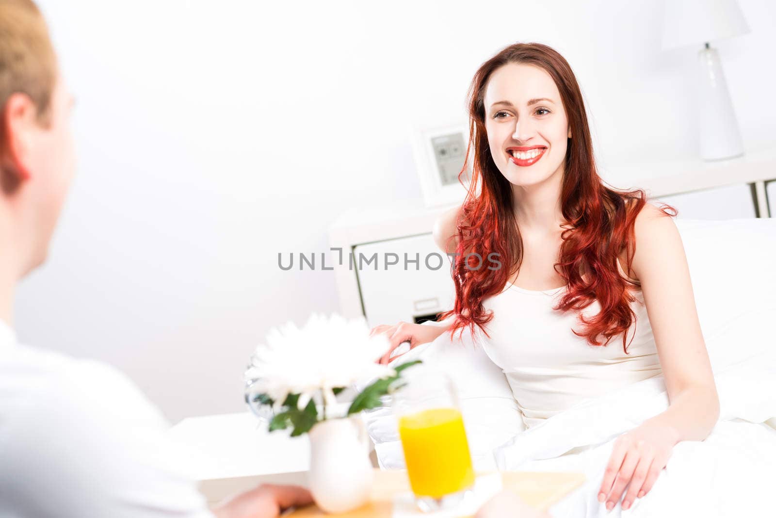 man brought his girlfriend breakfast in bed, holding a tray of juice and breakfast