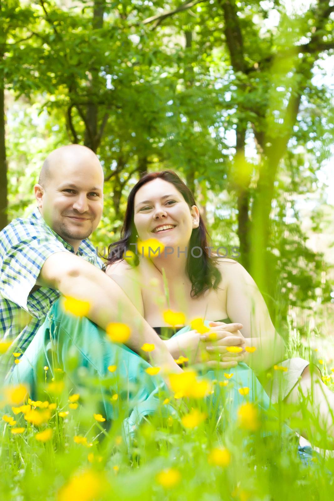 Happy young couple is sitting in a field of buttercups