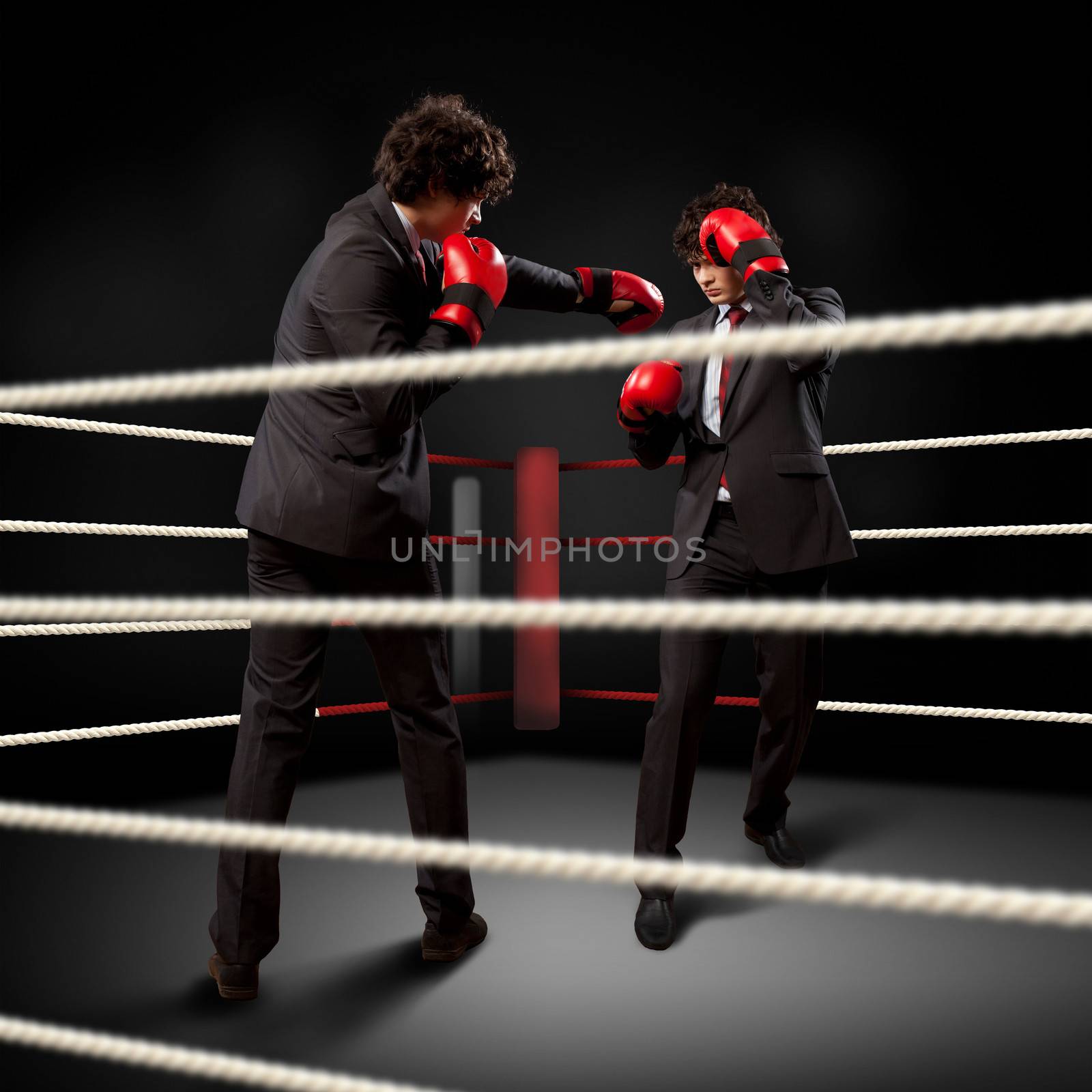 Two young businessman boxing againts dark background . conceptual collage