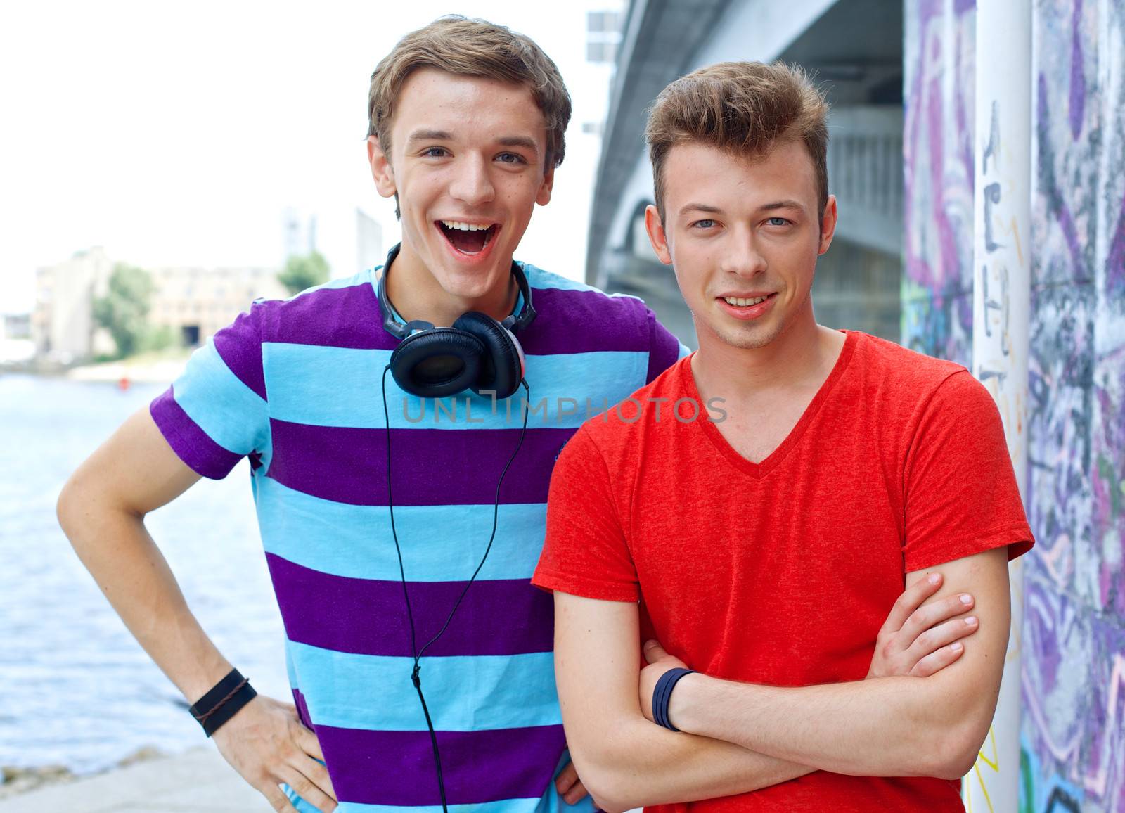 Portrait of happy two teens boys by painted wall looking at camera