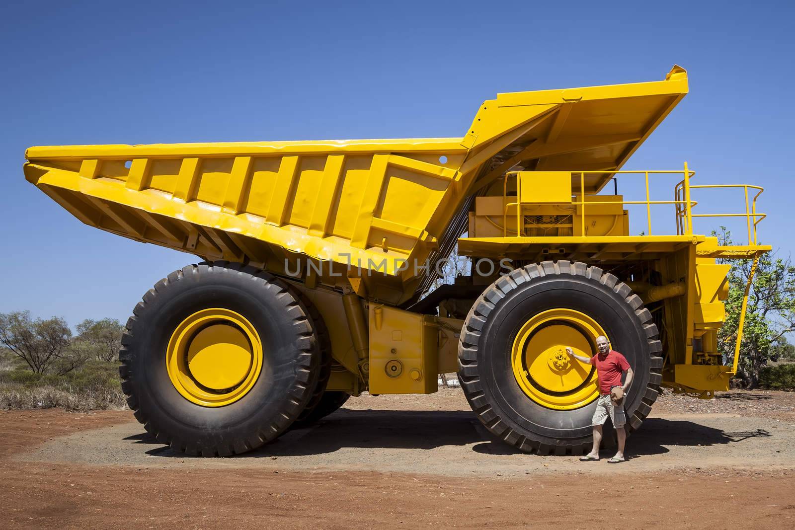 An image of a big yellow transporter and a man in front of a wheel