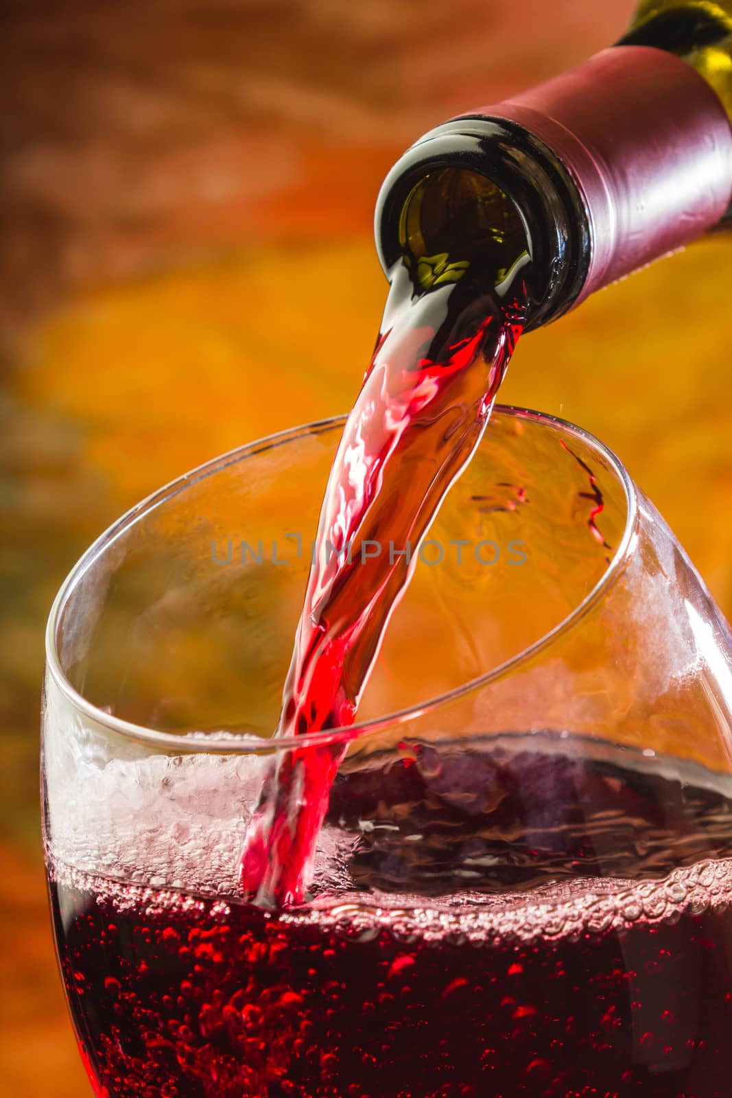 Wine pours into the glass of the bottle on a colored background