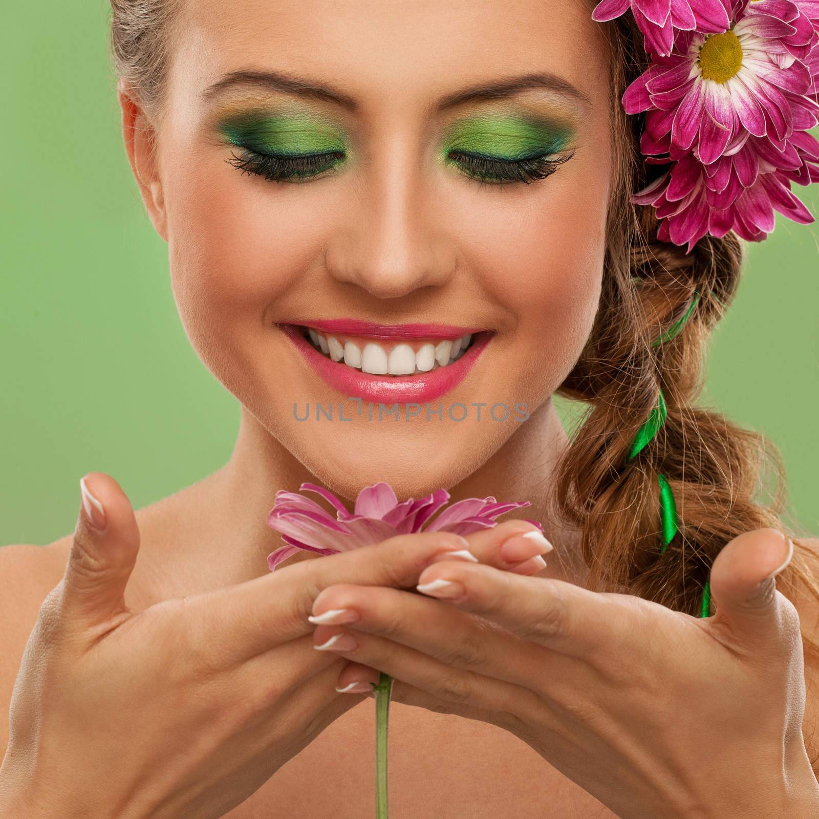 Beautiful woman with makeup and flowers over green background