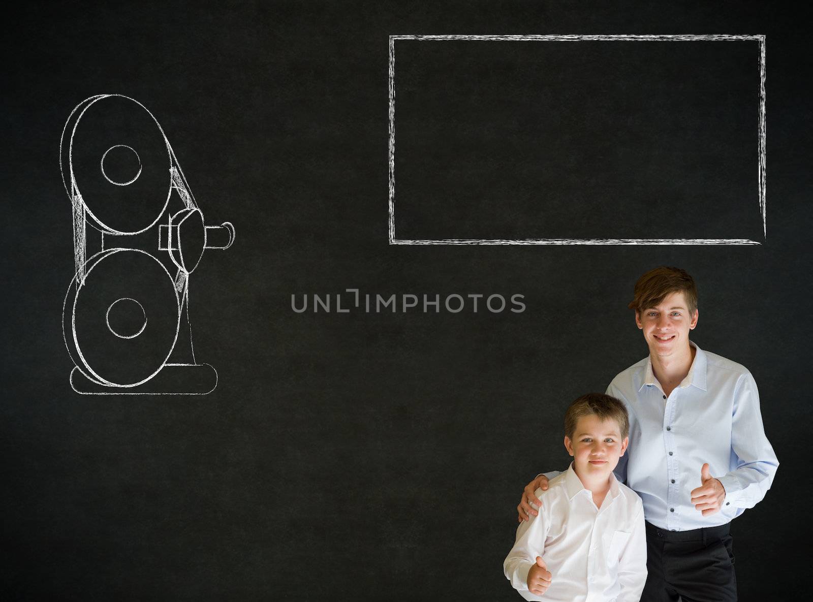 Thumbs up boy dressed up as business man with teacher man and retro chalk film projector on blackboard background