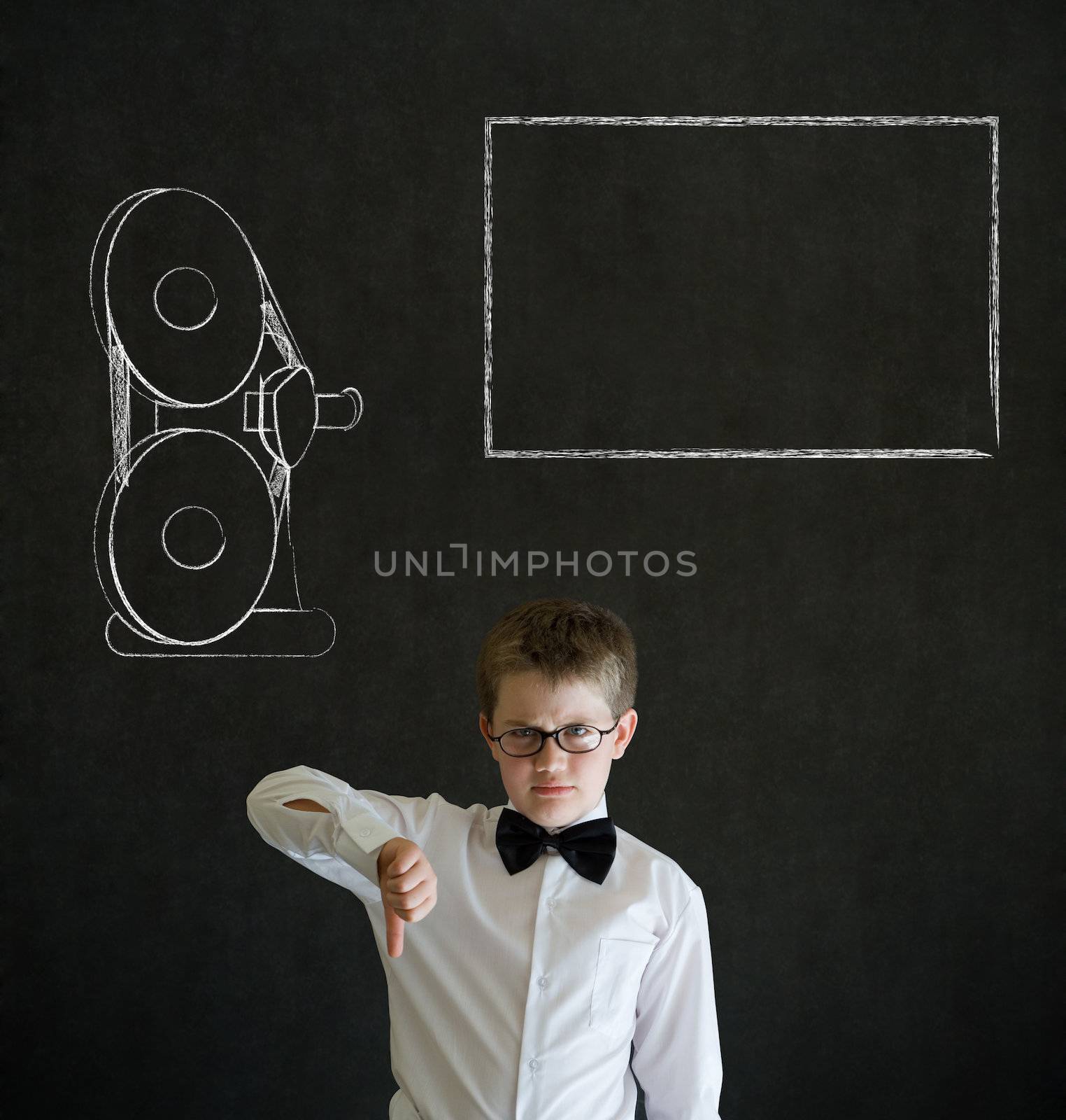Thumbs down boy dressed up as business man with retro chalk film projector on blackboard background