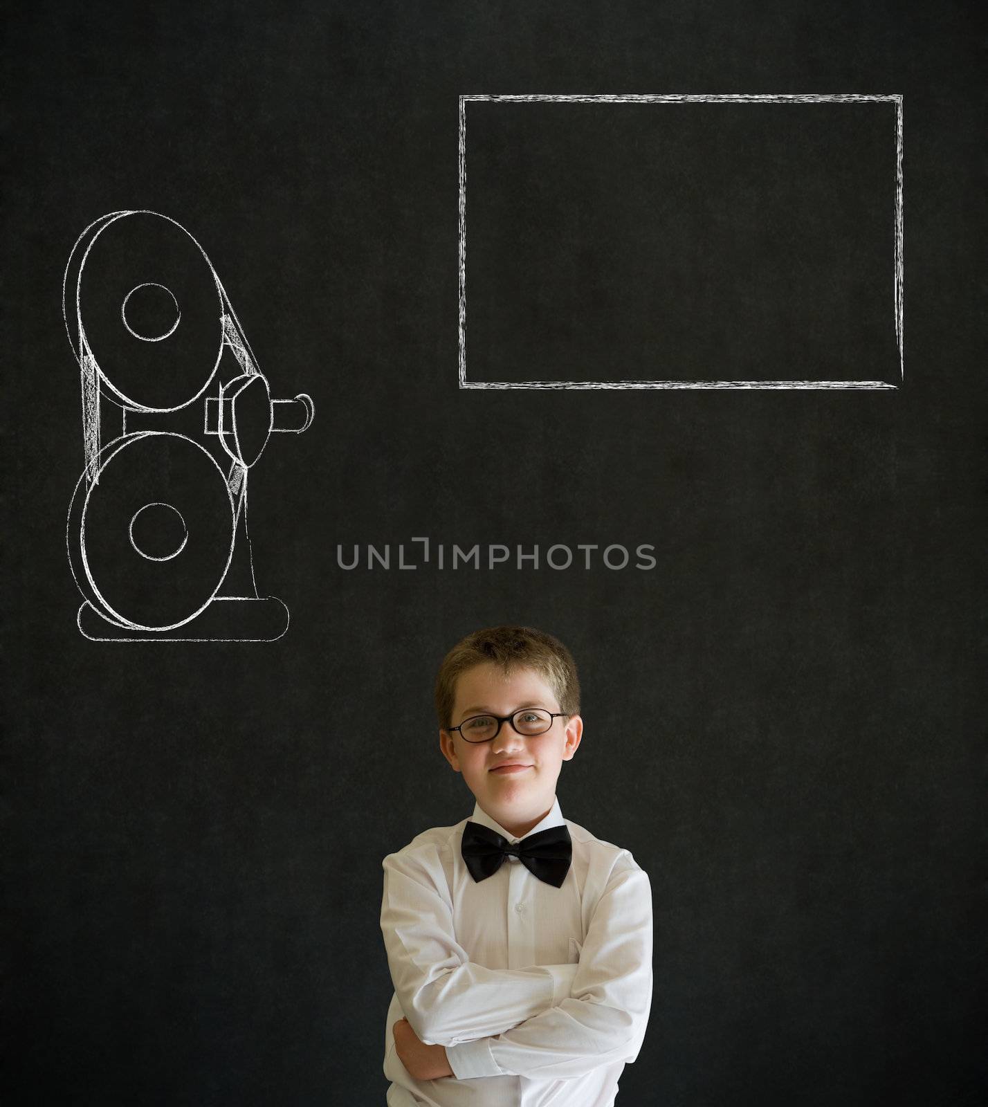 Thinking boy dressed up as business man with retro chalk film projector on blackboard background