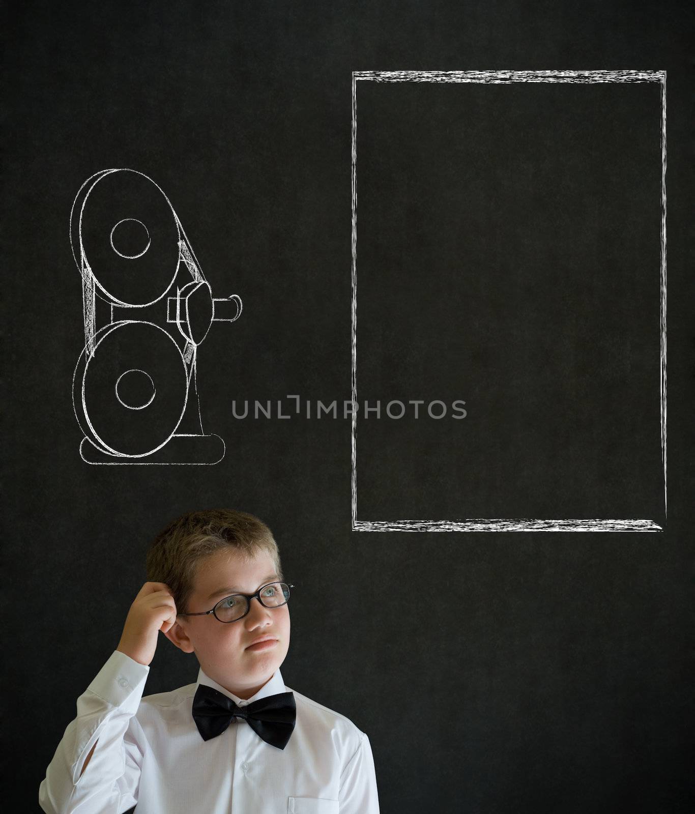 Scratching head thinking boy dressed up as business man with retro chalk film projector on blackboard background
