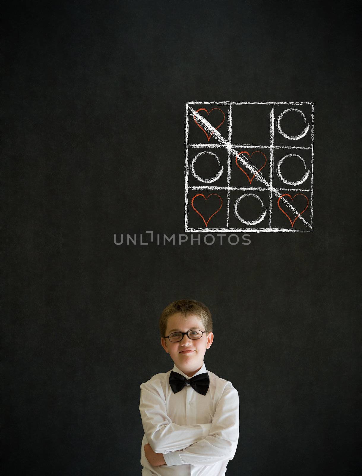 Thinking boy dressed up as business man with chalk tic tac toe love valentine concept on blackboard background